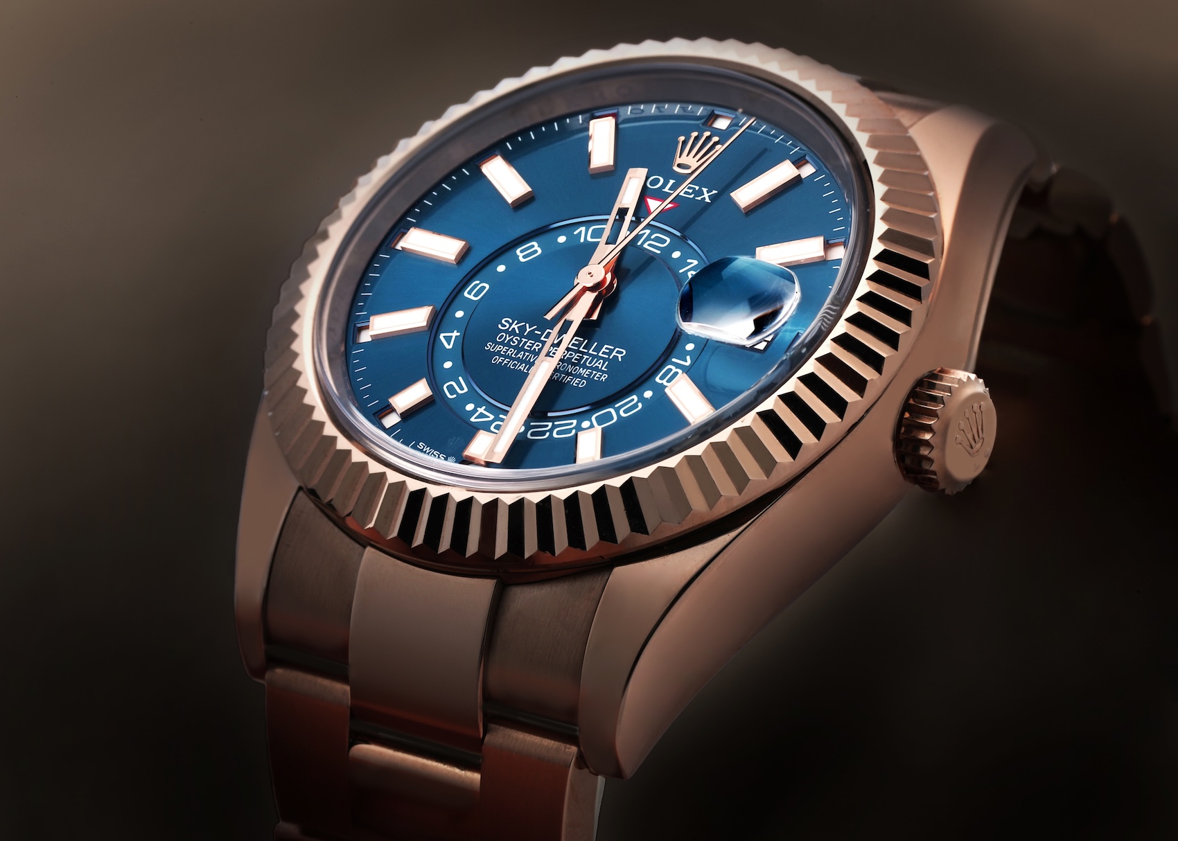  Detailed macro view of the Rolex Sky-Dweller in 18k Everose gold, highlighting the "Blue-Green" dial, rose gold hands, and the off-center 24-hour GMT disc.