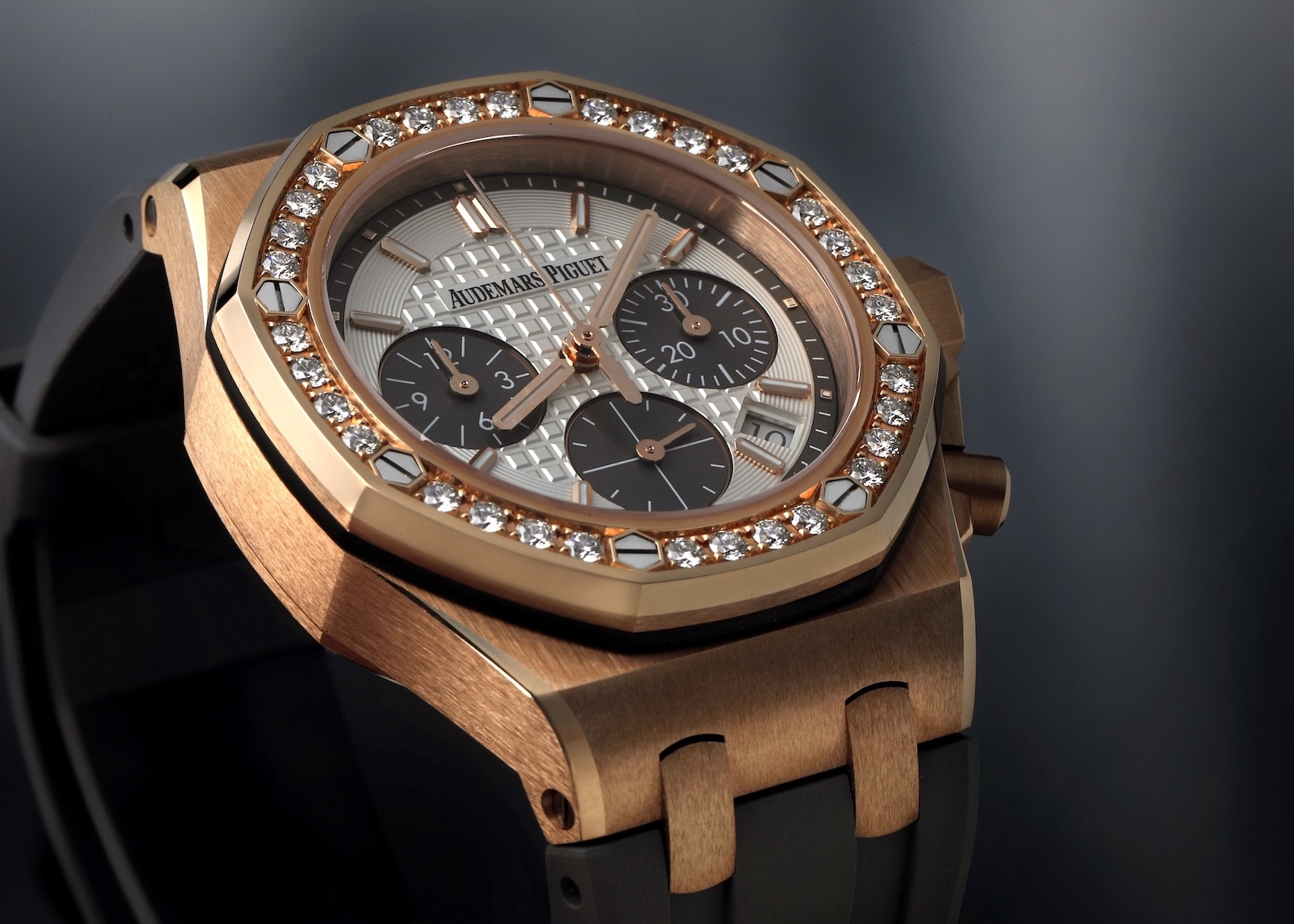 An Audemars Piguet Royal Oak Offshore ladies' chronograph in rose gold with a diamond-set bezel, a silver Méga Tapisserie dial, and a black rubber strap.