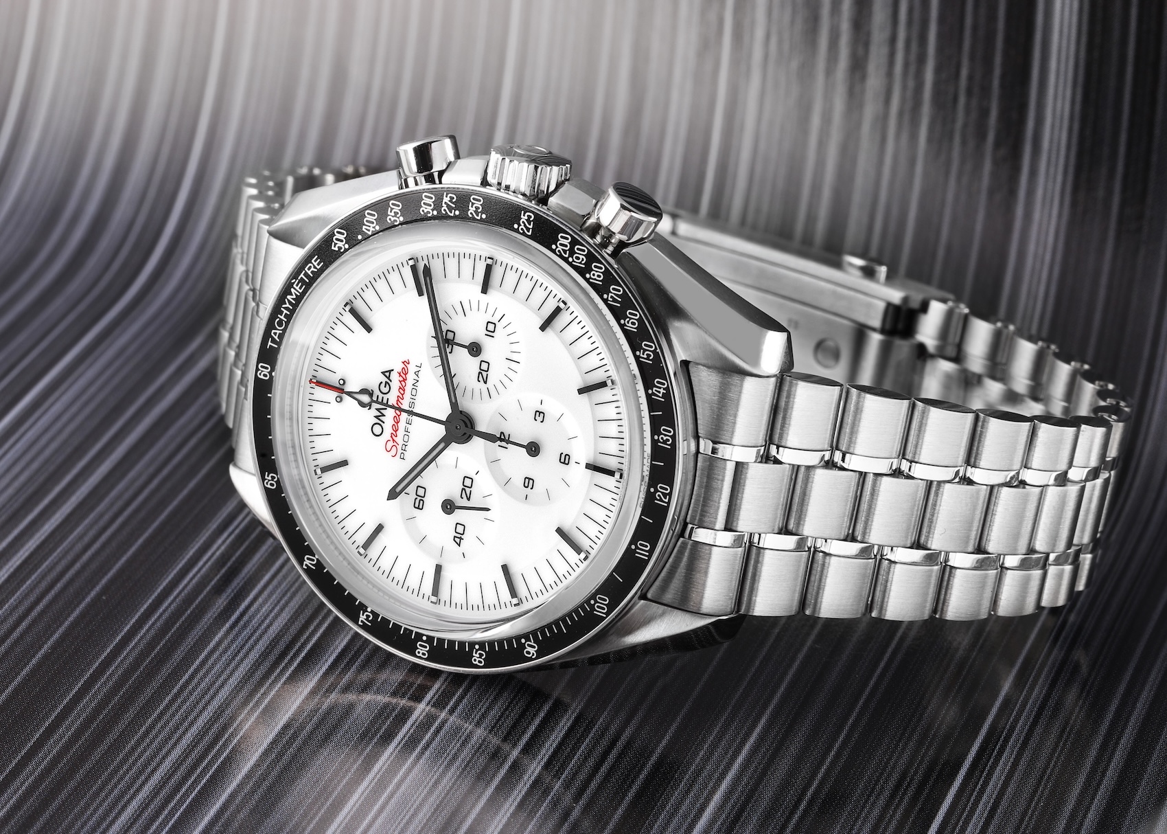 A side profile of the Omega Speedmaster Professional Moonwatch featuring a white lacquered dial and a black tachymeter bezel on a stainless steel bracelet.