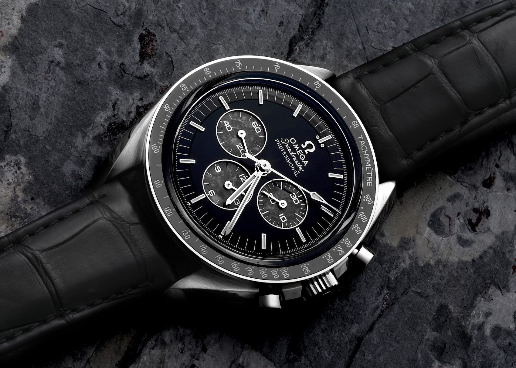 A close-up of an Omega Speedmaster Professional in platinum, featuring a black onyx dial with three sub-dials made from moon meteorite.