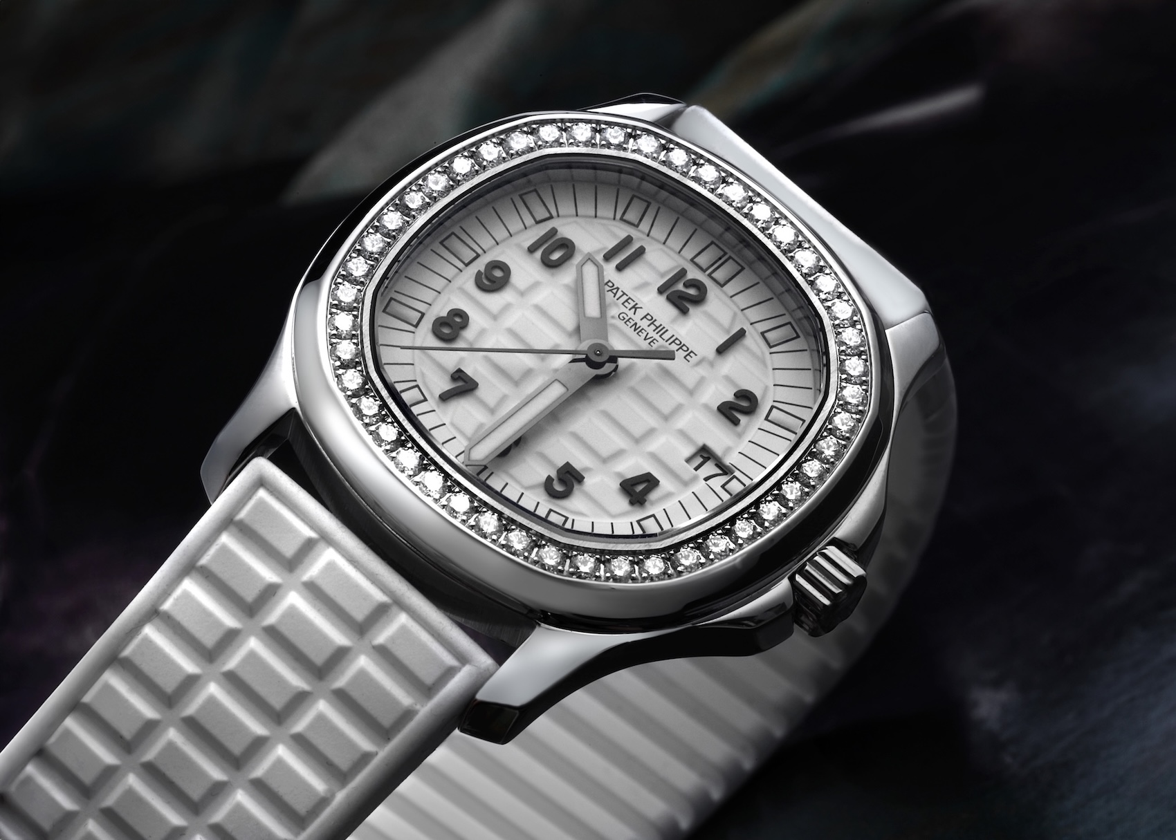 A Patek Philippe Aquanaut Luce 5067A ladies' watch with a stainless steel case, a brilliant-cut diamond bezel, and a white embossed "grenade" pattern dial with a matching white rubber strap.