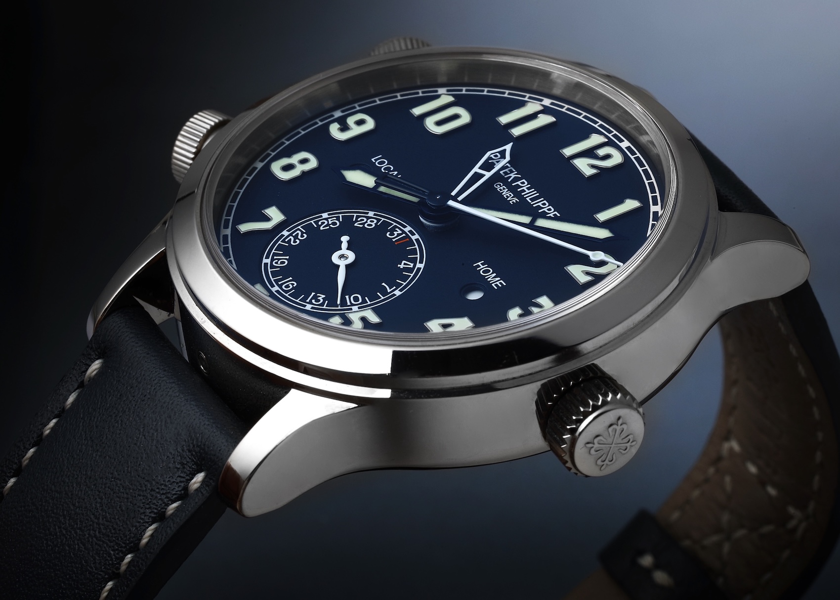 A Patek Philippe 5524G Calatrava Pilot Travel Time in white gold with a textured navy blue dial, large luminous numerals, and dual-time zone pushers.