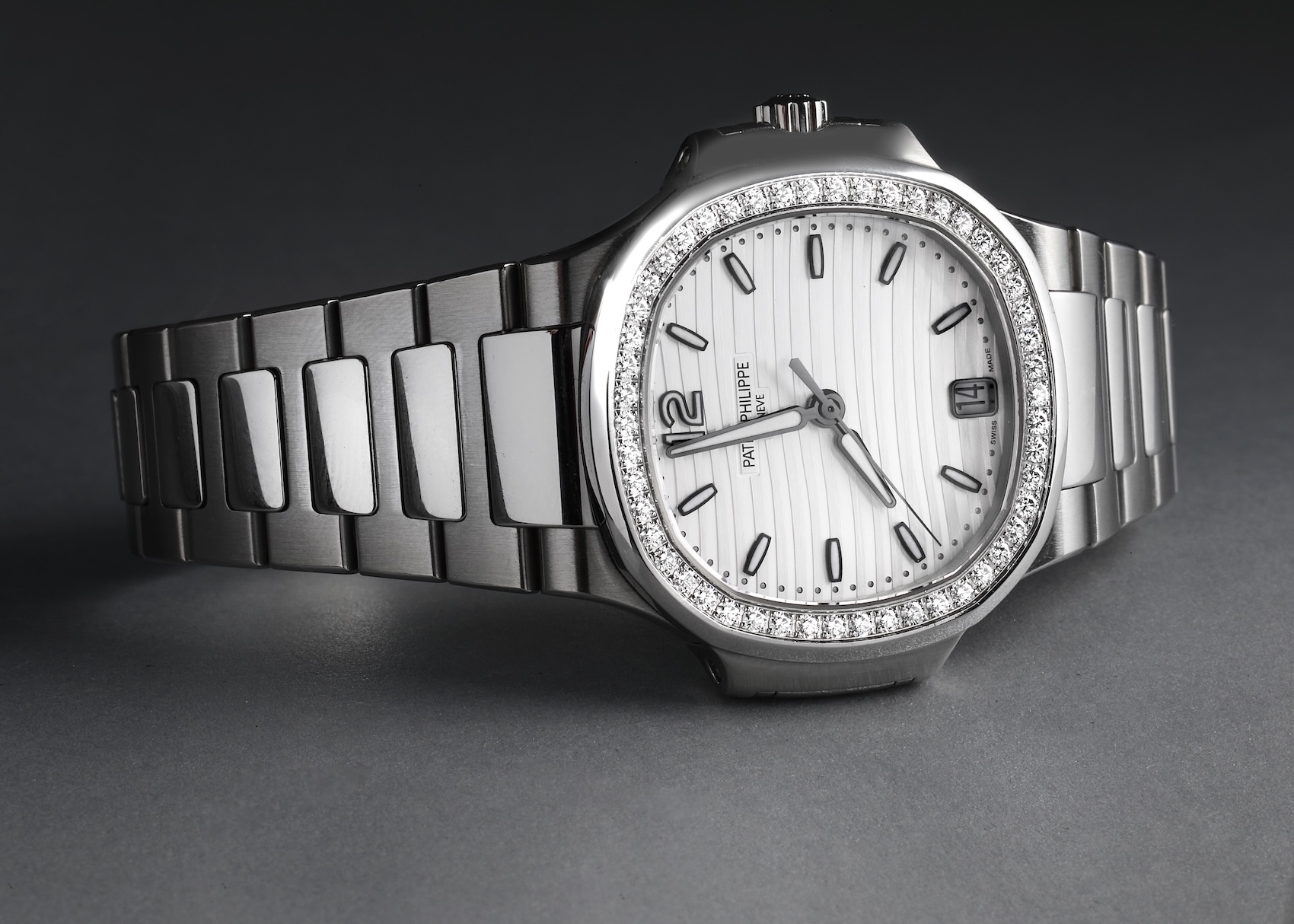A stainless steel Patek Philippe Nautilus ladies' watch featuring a horizontally embossed silver-white dial and a sparkling diamond-set bezel.