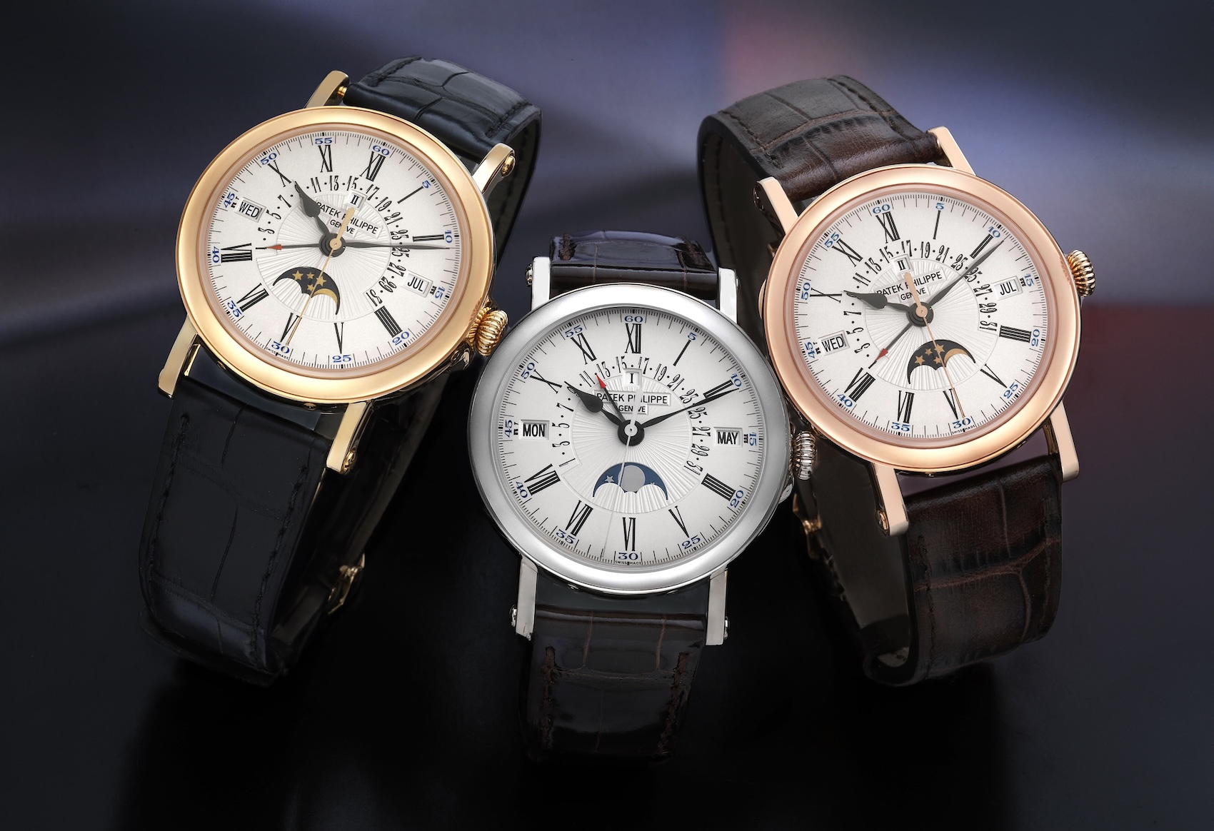 Three Patek Philippe 5159 watches displayed together in yellow gold, white gold, and rose gold.