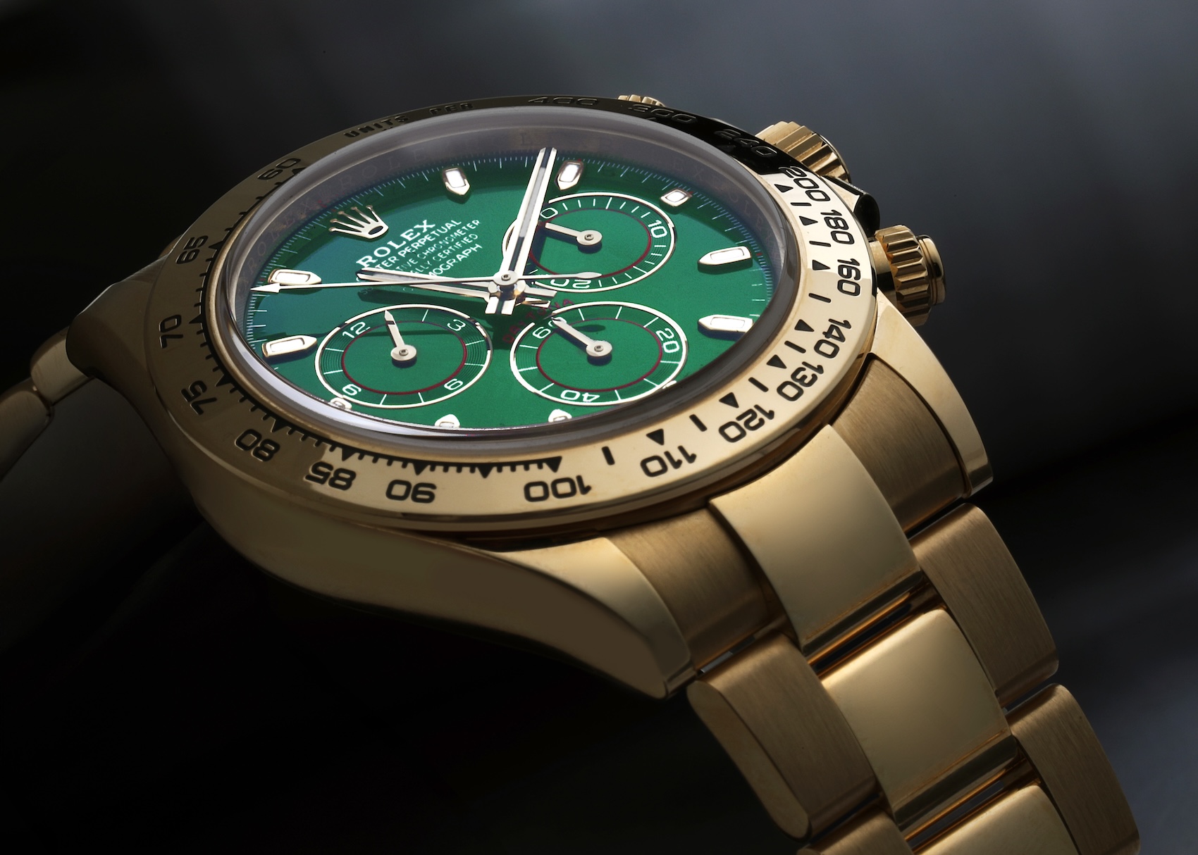 A close-up, angled view of the Rolex Daytona 116508 in 18k yellow gold featuring a vibrant green sunburst dial and a polished tachymeter bezel.