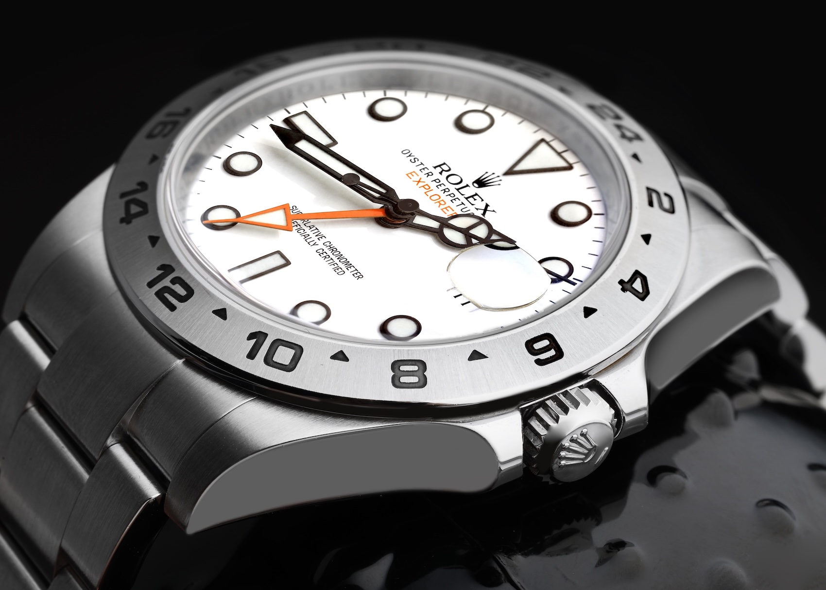 Close-up of a Rolex Explorer II with a crisp white "Polar" dial, featuring a bright orange GMT hand and a fixed stainless steel 24-hour bezel.