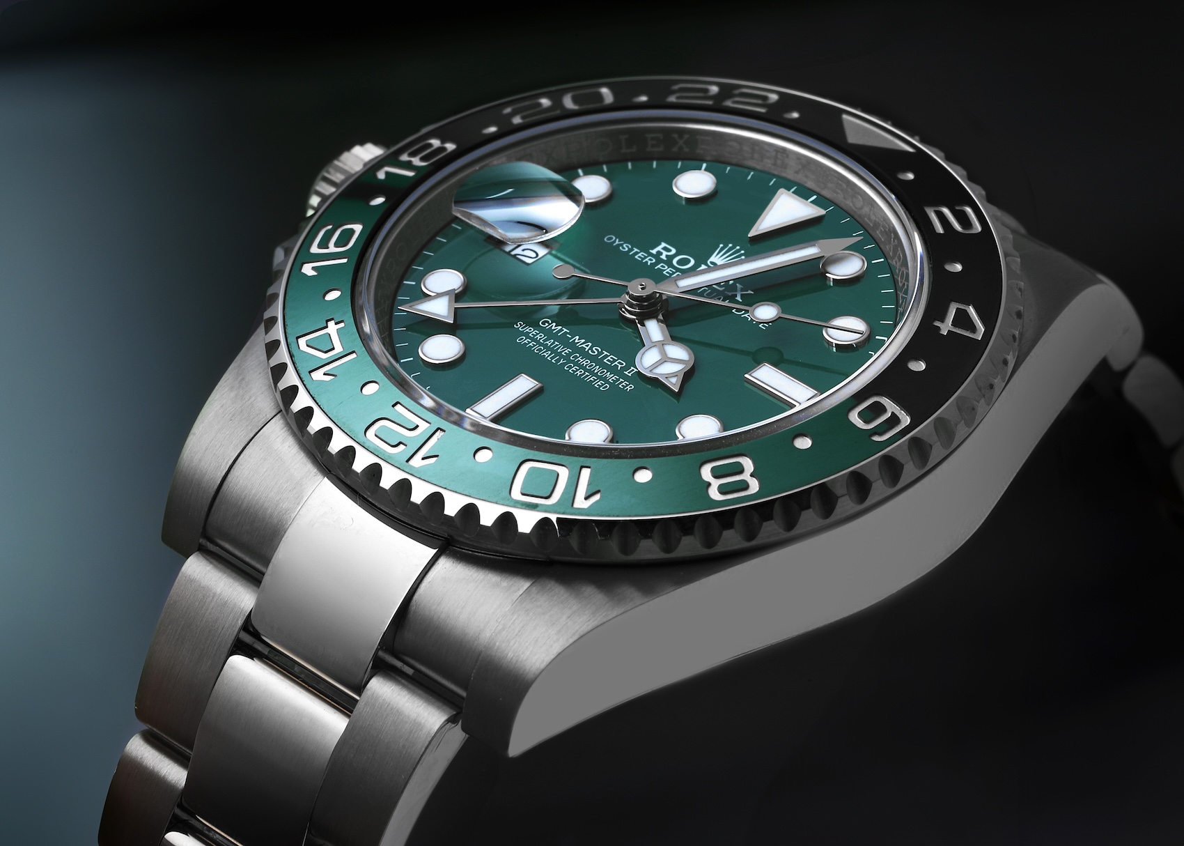 A close-up, angled view of a left-handed Rolex GMT-Master II "Sprite" in white gold, featuring a green and black ceramic bezel and a sunray green dial.