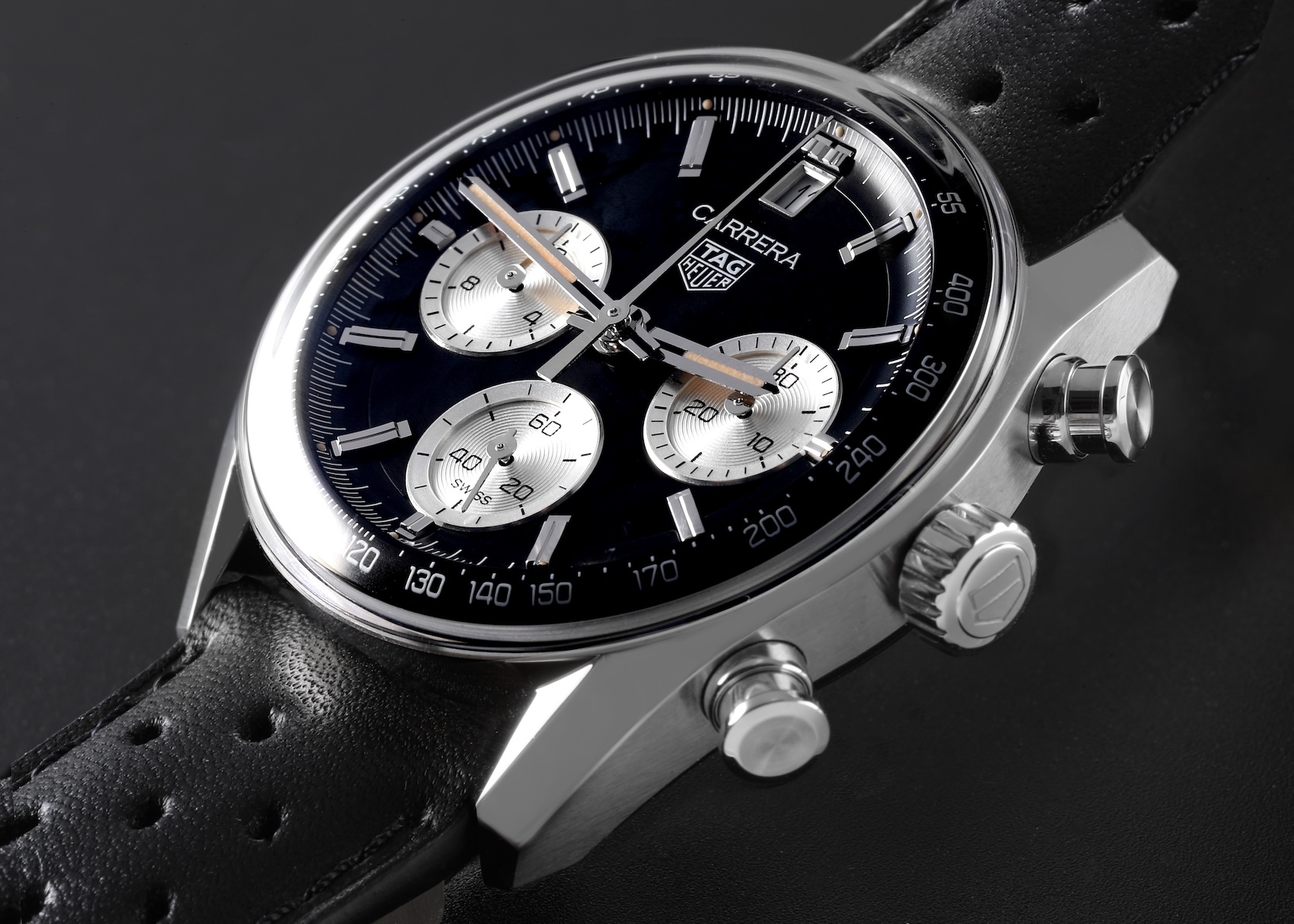  A TAG Heuer Carrera Chronograph with a "reverse panda" dial—black background with silver sub-dials—under a prominent domed sapphire "glassbox" crystal.