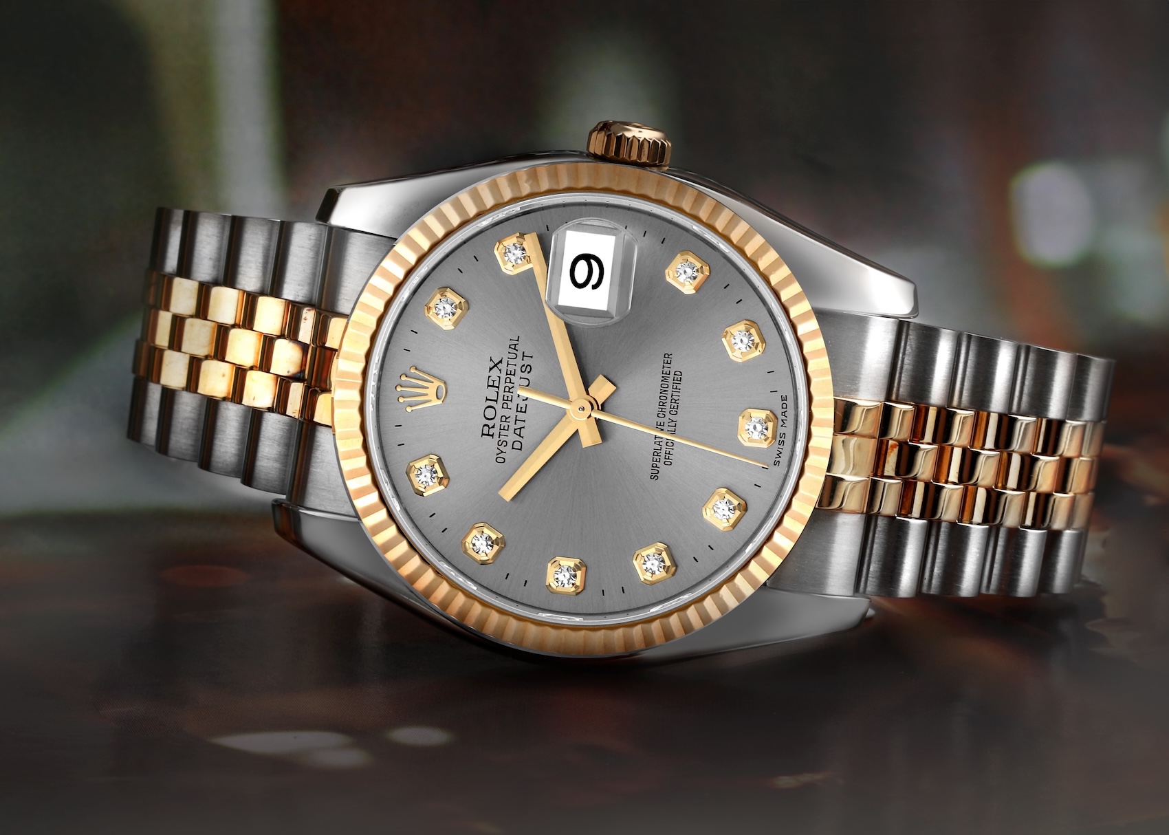  A close-up of a two-tone Rolex Datejust 36 with a fluted yellow gold bezel, grey sunburst dial, and diamond hour markers on a Jubilee bracelet.