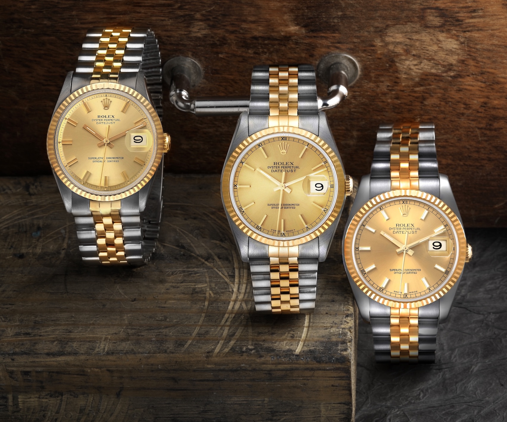 Three vintage and modern Rolex Datejust 36mm watches with champagne dials and two-tone Jubilee bracelets arranged on a wooden surface.
