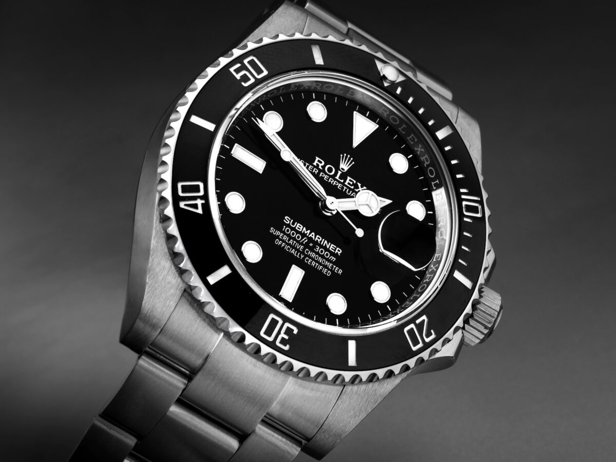 A high-contrast, professional studio shot of the Rolex Submariner 126610LN, highlighting the "Submariner" text and the Cyclops lens over the date window.