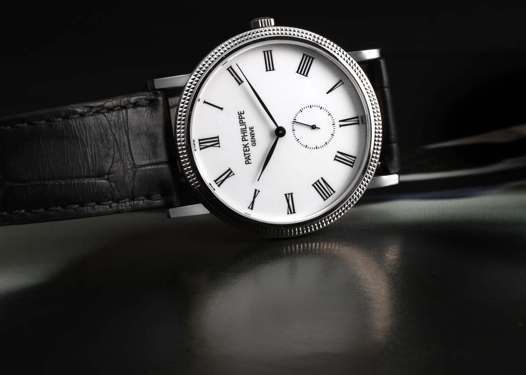 A front-facing view of the Patek Philippe 5119G in white gold with a black leather strap, showcasing the contrast between the monochromatic white gold hobnail bezel and the crisp white dial.