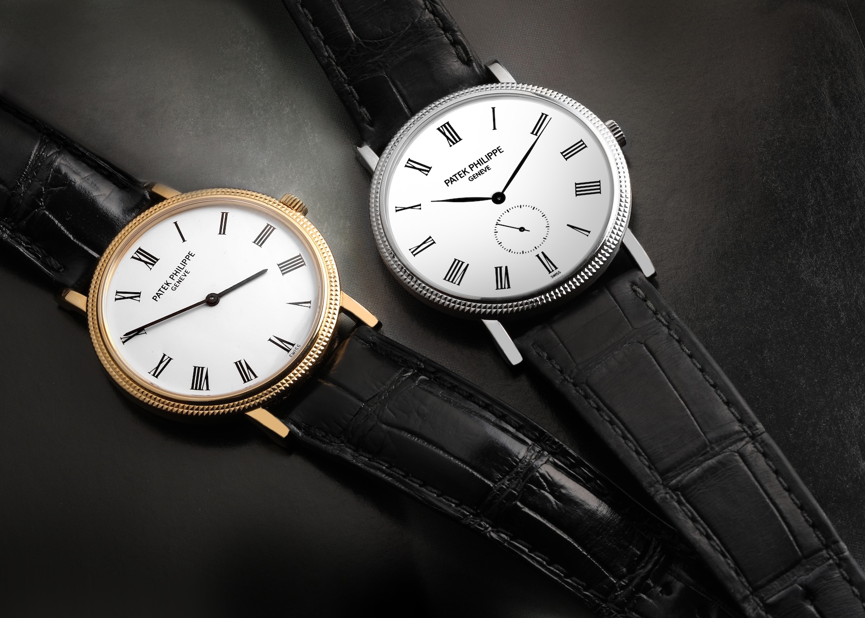 Two Patek Philippe Reference 6119 watches—one in white gold and one in rose/yellow gold—lying side-by-side on a dark surface to show the updated, larger 39mm case size.
