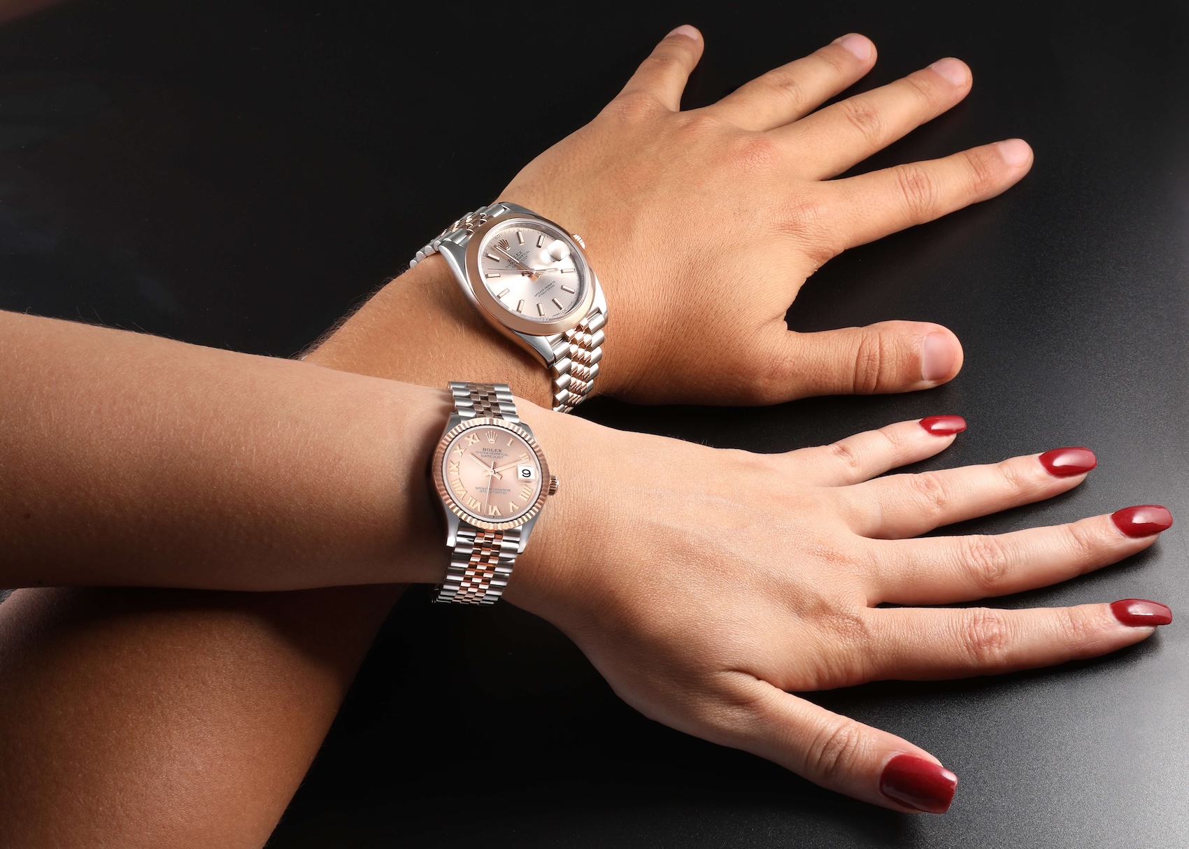 Couple wearing matching Rolex Datejust watches on wrist, showing the two-tone steel and rose gold finish and jubilee bracelets.