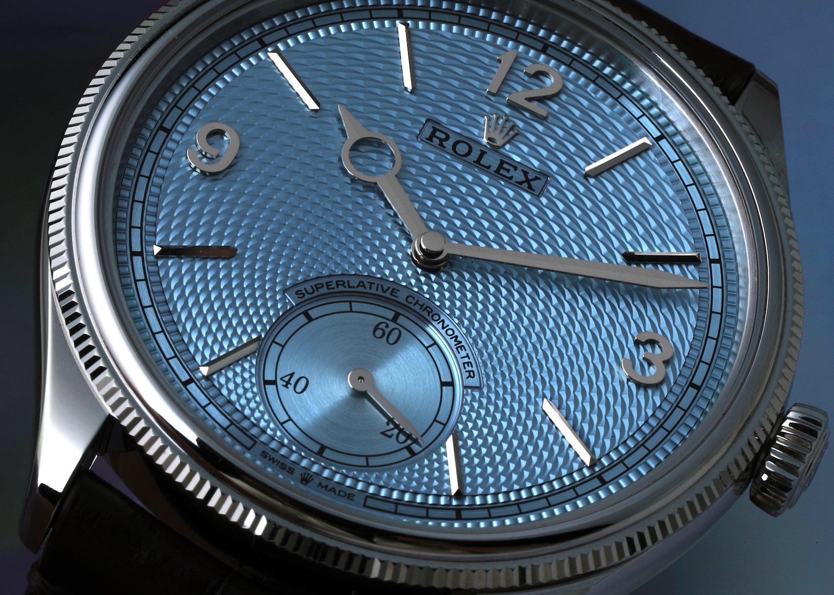  Extreme macro photography of the Rolex 1908 platinum dial, highlighting the applied white gold Rolex coronet, the sword hands, and the intricate, three-dimensional rice-grain guilloché pattern.