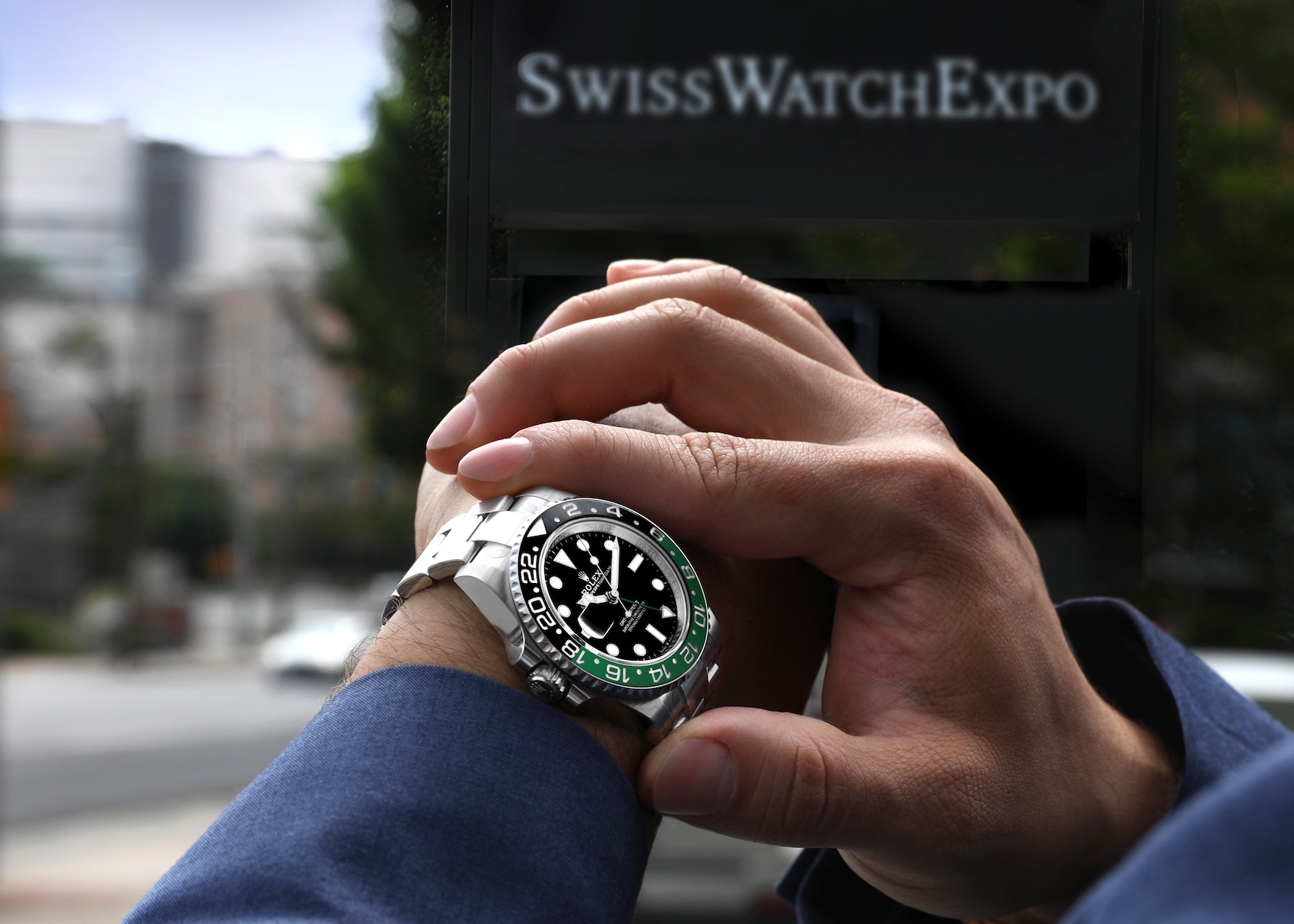 A man wearing a Rolex GMT-Master II Sprite reference 126720VTNR in Oystersteel on an Oyster bracelet, adjusting the watch on his wrist outdoors.