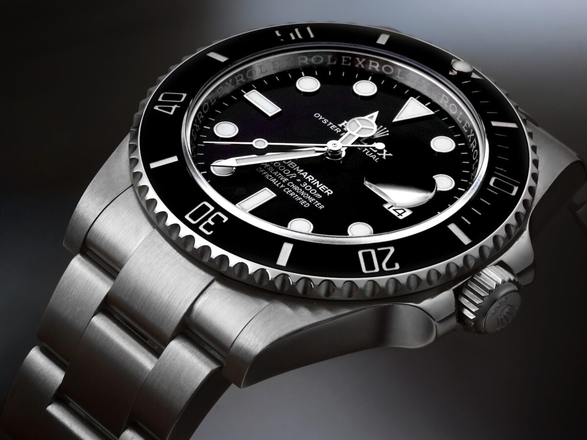 Studio close-up of a stainless steel Rolex Submariner Date with a black ceramic bezel and black dial, highlighting the date window and Oyster bracelet.