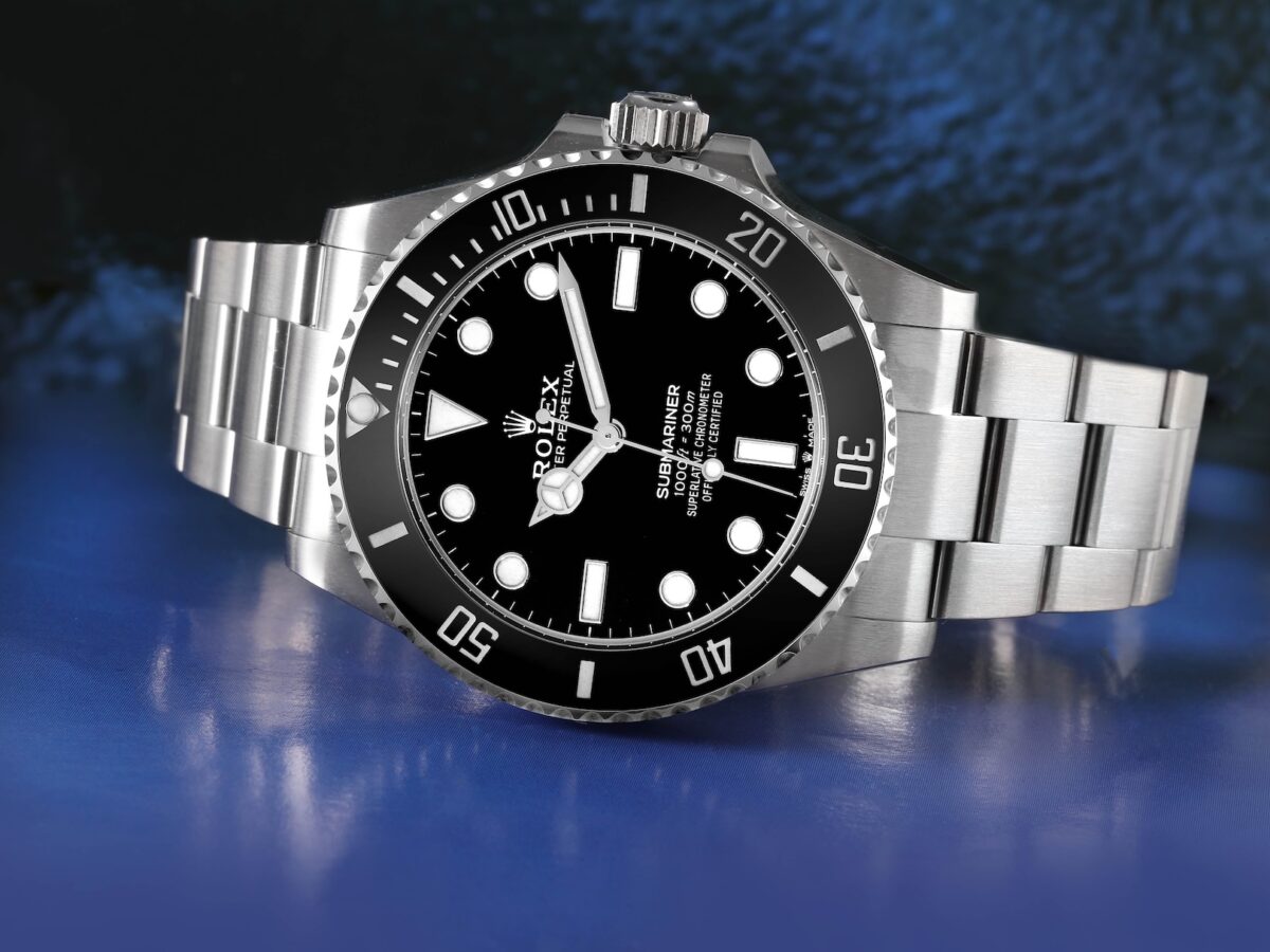 A modern Rolex Submariner Date in stainless steel resting on a blue, water-like surface, representing 100 years of waterproof history.