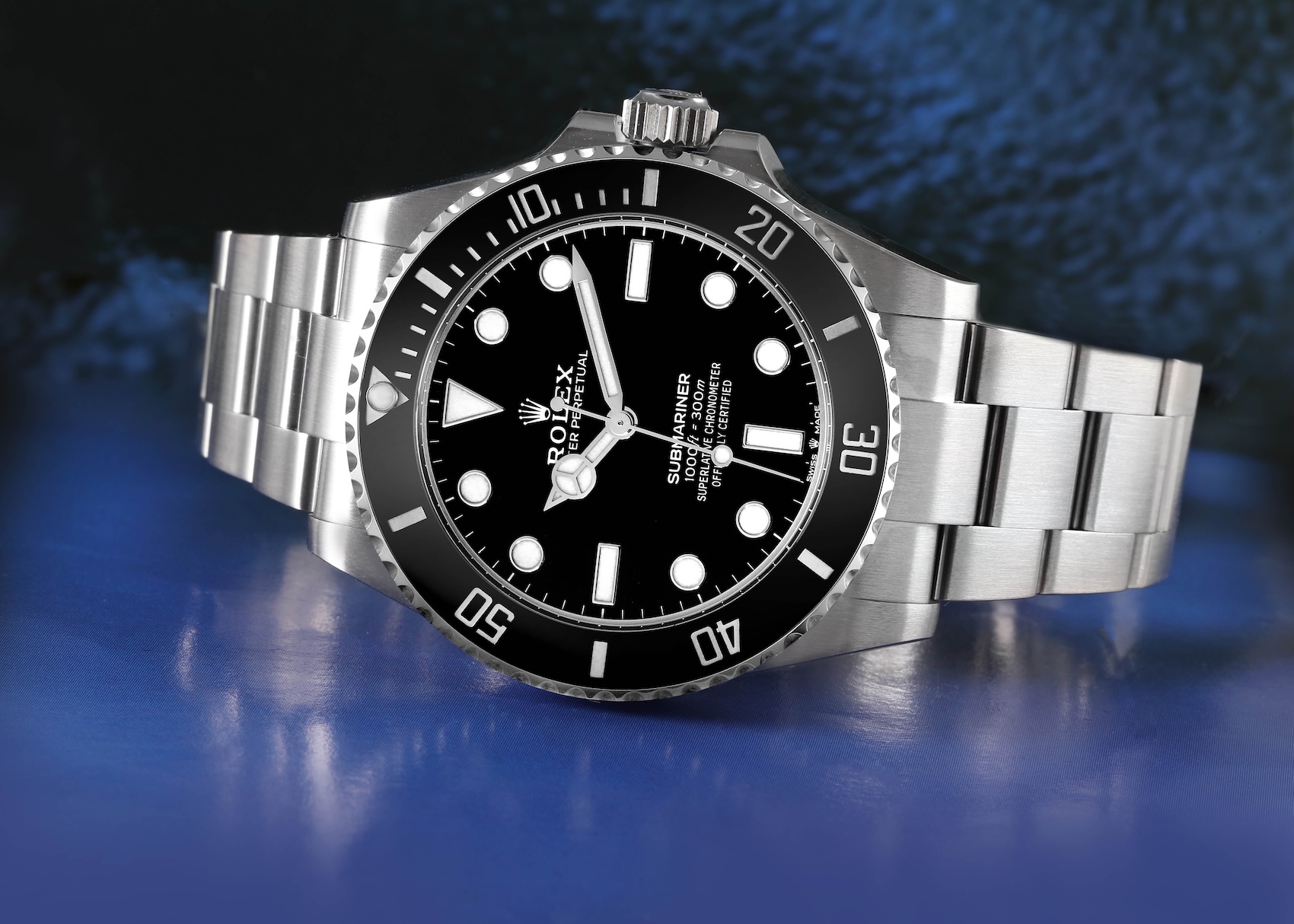 A modern Rolex Submariner Date in stainless steel resting on a blue, water-like surface, representing 100 years of waterproof history.