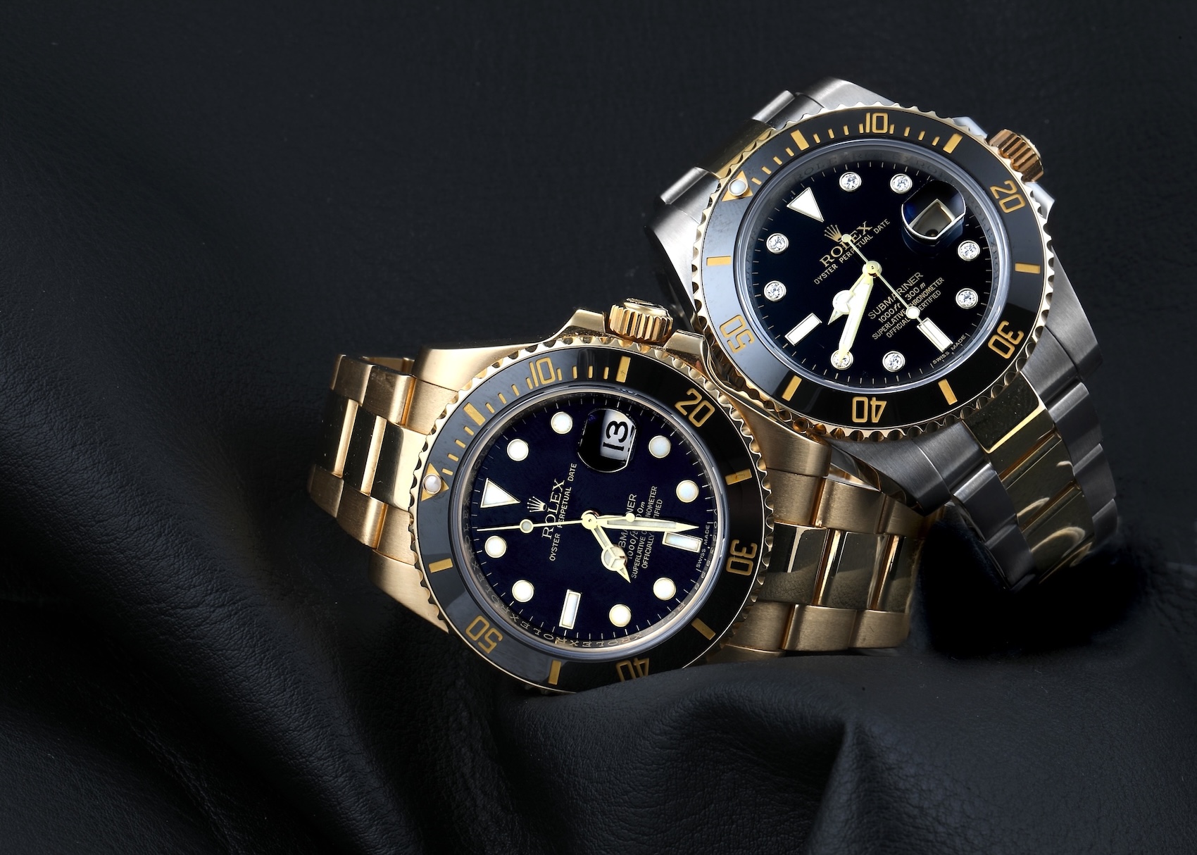 Two Rolex Submariners, one in solid yellow gold and one in two-tone, showing their date functions.