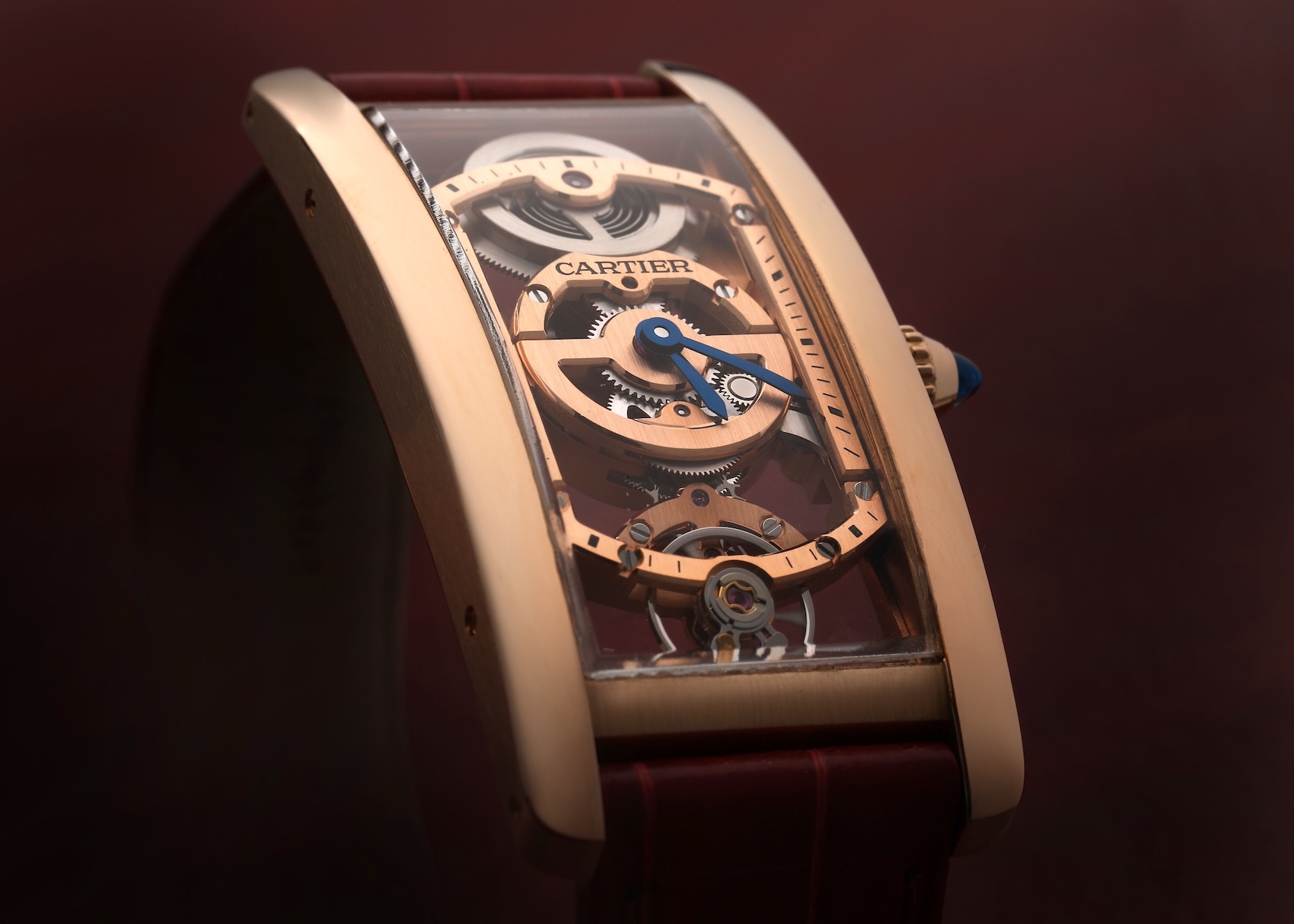 Angled view of a rose gold Cartier Tank Cintrée Skeleton watch revealing its custom curved Swiss mechanical movement.