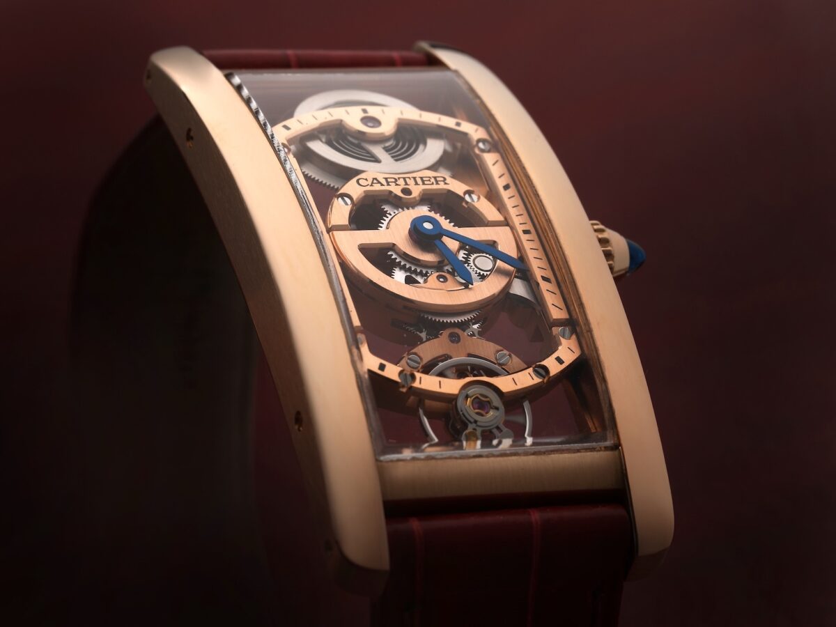 Angled view of a rose gold Cartier Tank Cintrée Skeleton watch revealing its custom curved Swiss mechanical movement.