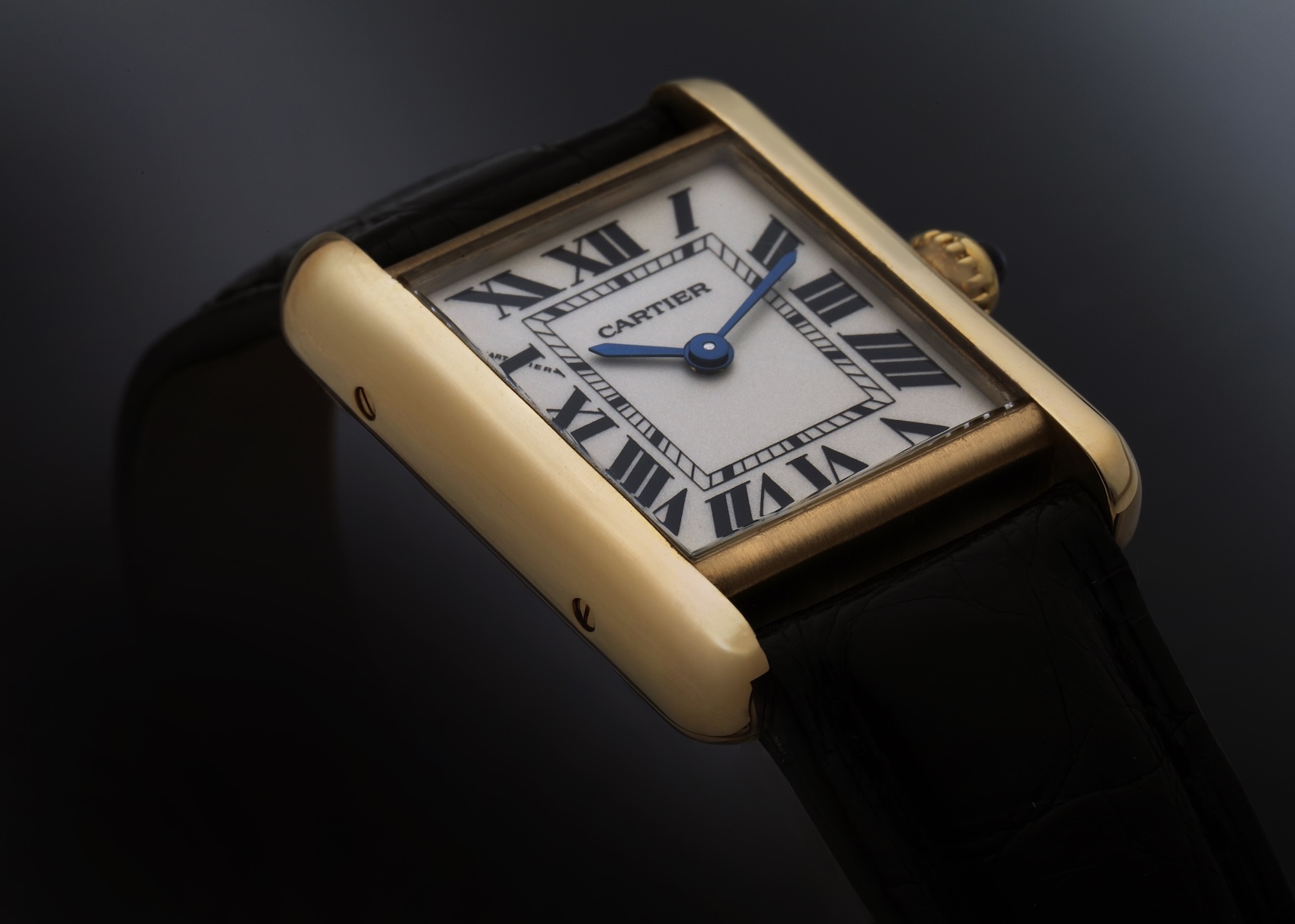 Classic Cartier Tank Louis small model in yellow gold with a Roman numeral dial on a black leather strap.