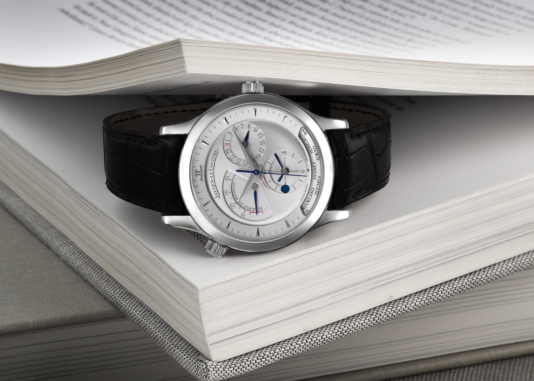 Stainless steel Jaeger-LeCoultre Master Geographic world time watch resting inside a book.