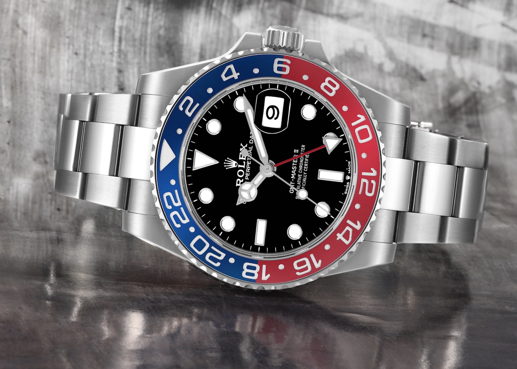 A front view of the modern stainless steel Rolex GMT-Master II Pepsi (Ref. 126710BLRO) featuring the ceramic bezel and an Oyster bracelet, set against a blurred gray architectural backdrop.