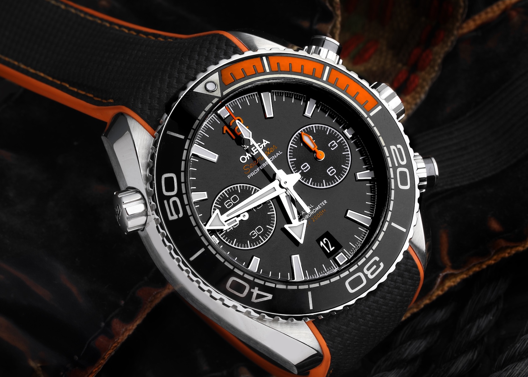 Close-up of an Omega Seamaster Planet Ocean Chronograph emphasizing the black ceramic bezel with Liquidmetal diving scales and numerals that are impervious to scratching.