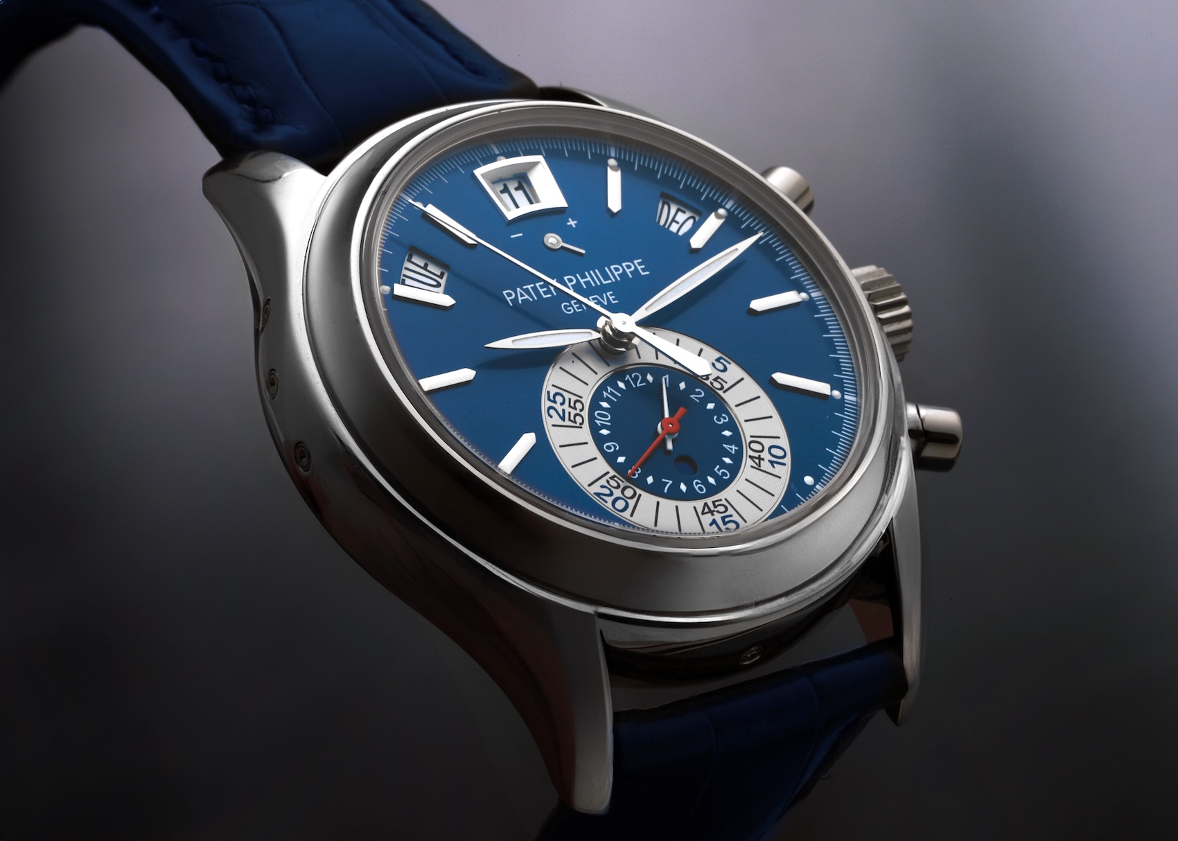 Close up angle of a Patek Philippe Complications Annual Calendar Chronograph Ref 5960P in platinum with a vibrant blue dial and blue leather strap.