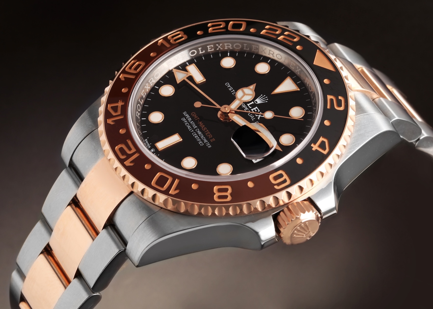 A close-up, angled view of the modern Rolex GMT-Master II Root Beer (ref. 126711CHNR) on a smooth brown background, highlighting the high polish of the Everose Rolesor.