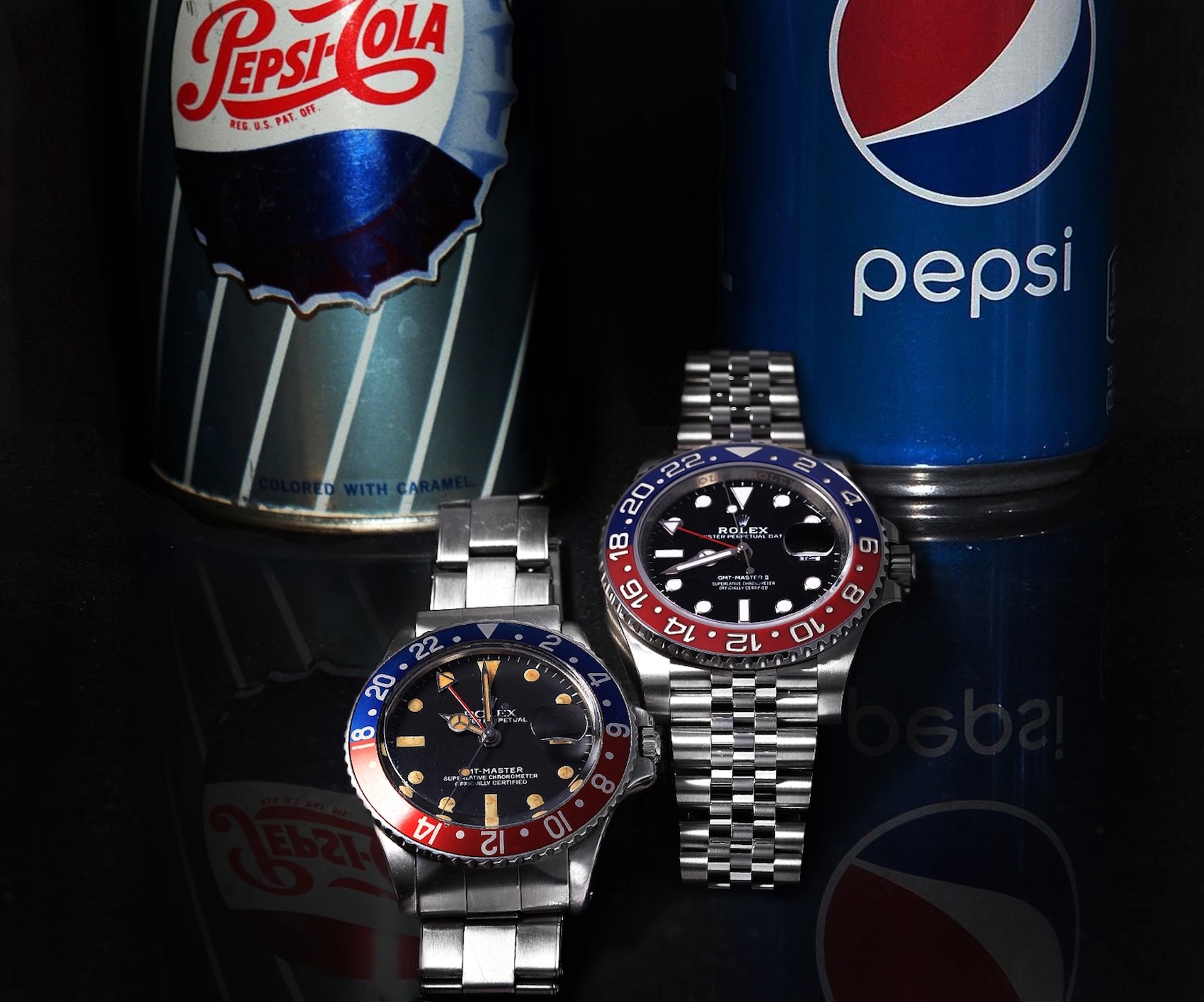 A side-by-side comparison of two Rolex watches standing in front of two Pepsi soda cans on a black reflective surface. On the left is a vintage GMT-Master (Ref. 1675) on an Oyster bracelet. On the right is a modern GMT-Master II (Ref. 126710BLRO) on a Jubilee bracelet.