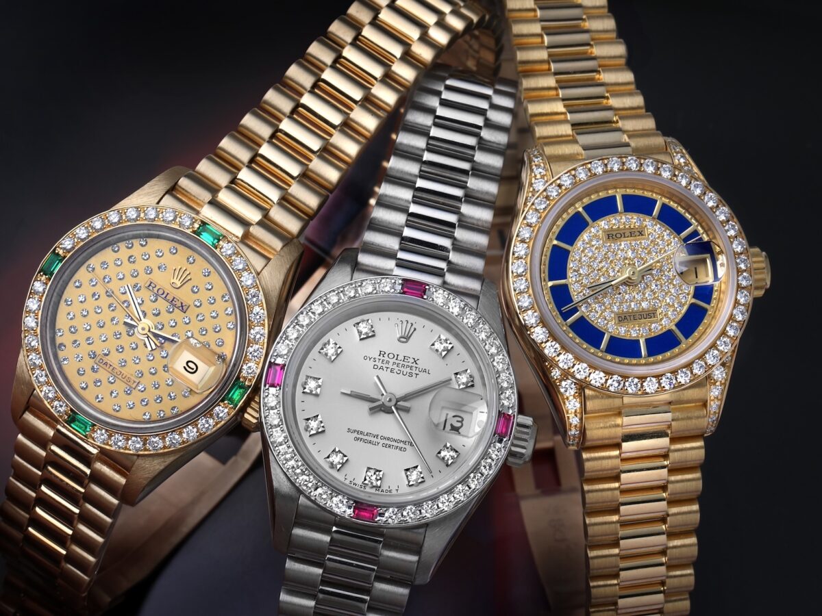 Group of three gem-set ladies Rolex Datejust President watches in yellow gold and white gold featuring diamonds, emeralds, rubies, and lapis lazuli.