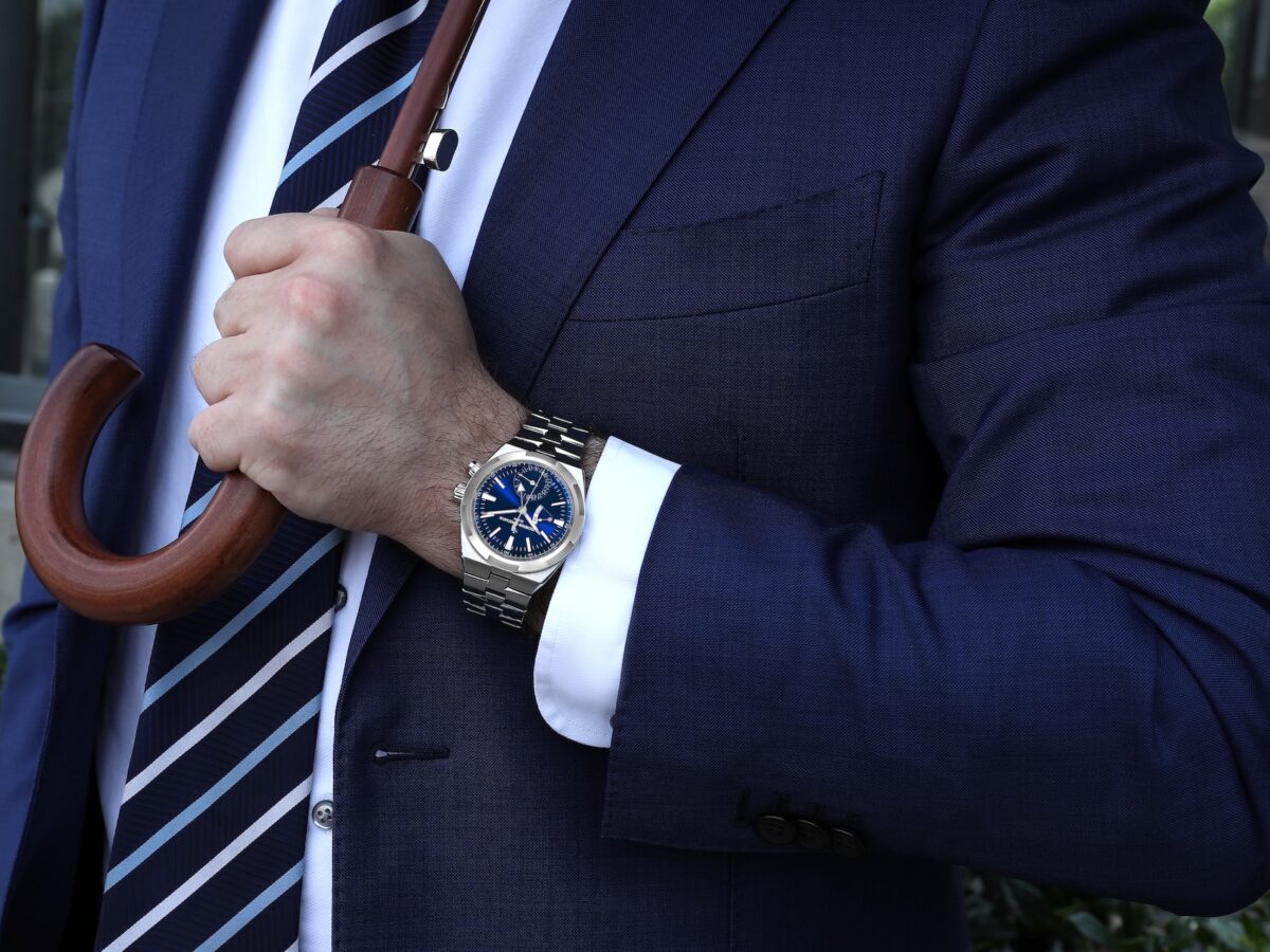 A man wearing a Vacheron Constantin Overseas Dual Time watch with a blue dial in a professional lifestyle setting.