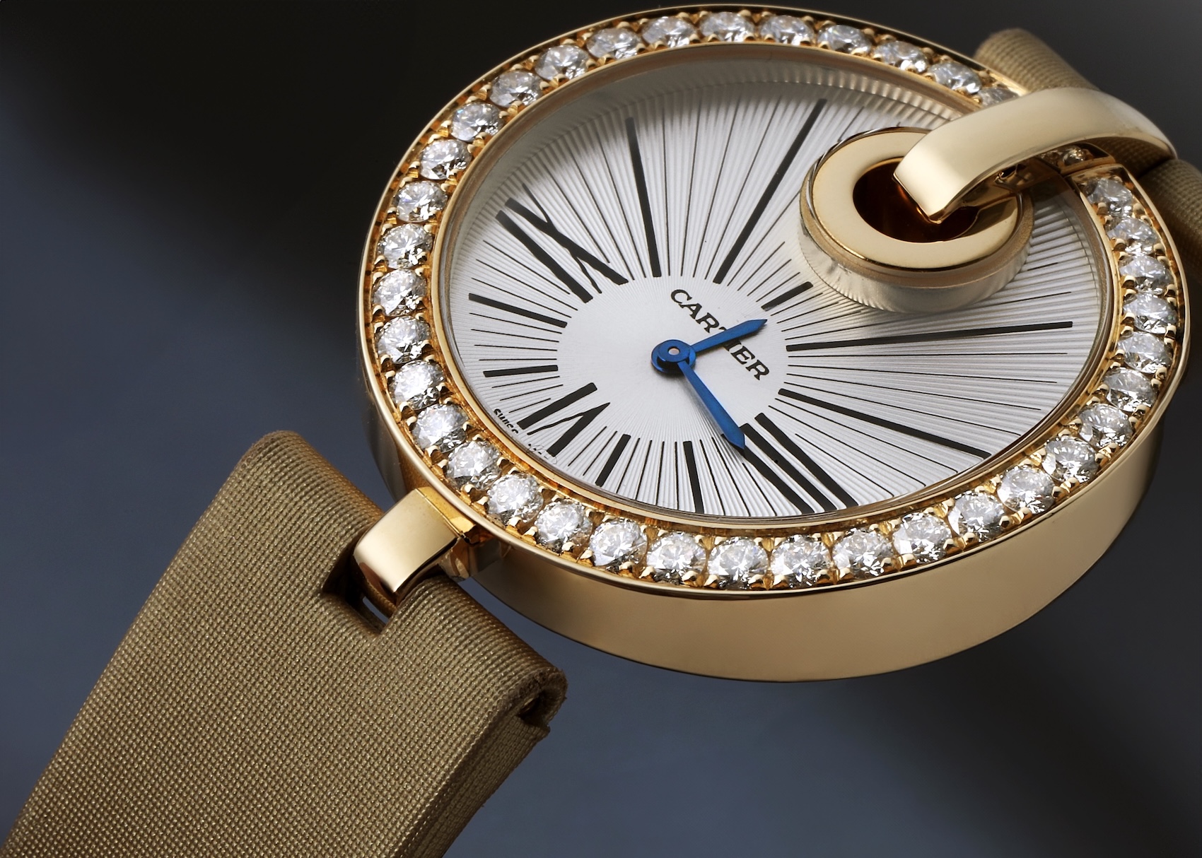 Close-up of the Cartier Captive yellow gold watch highlighting the diamond bezel and unique circular dial shape.
