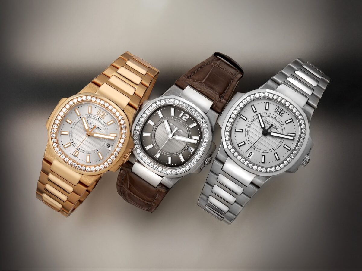 A lineup of three Patek Philippe Nautilus ladies' watches. Left: Rose gold with white dial and bracelet. Center: White gold with dark grey dial and brown leather strap. Right: Stainless steel with white dial and bracelet. All feature diamond bezels.