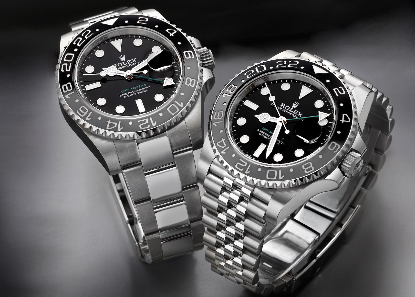 Two Rolex GMT-Master II Bruce Wayne grey and black bezel watches side by side, one on an Oyster bracelet and one on a Jubilee bracelet.