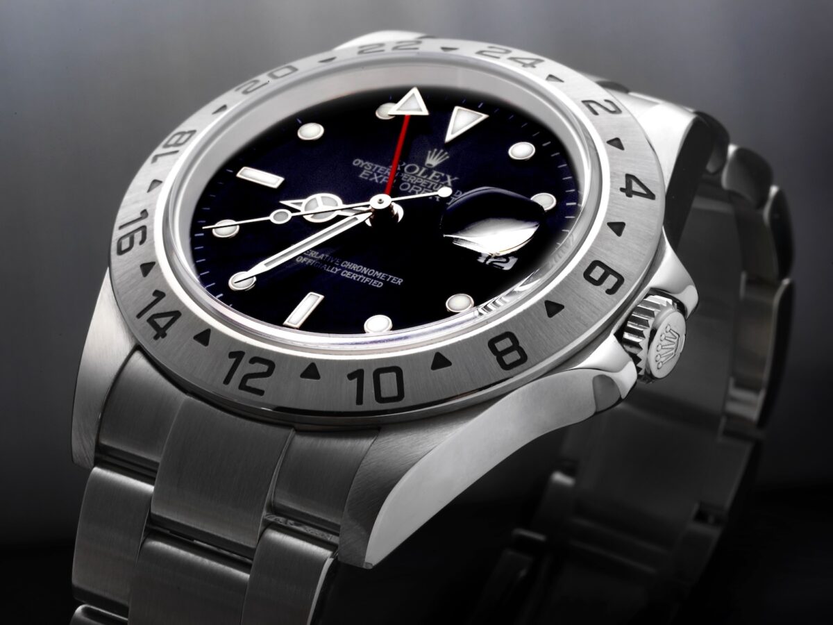 A close-up shot of a neo-vintage Rolex Explorer II Reference 16570 featuring a black dial and brushed steel 24-hour bezel.