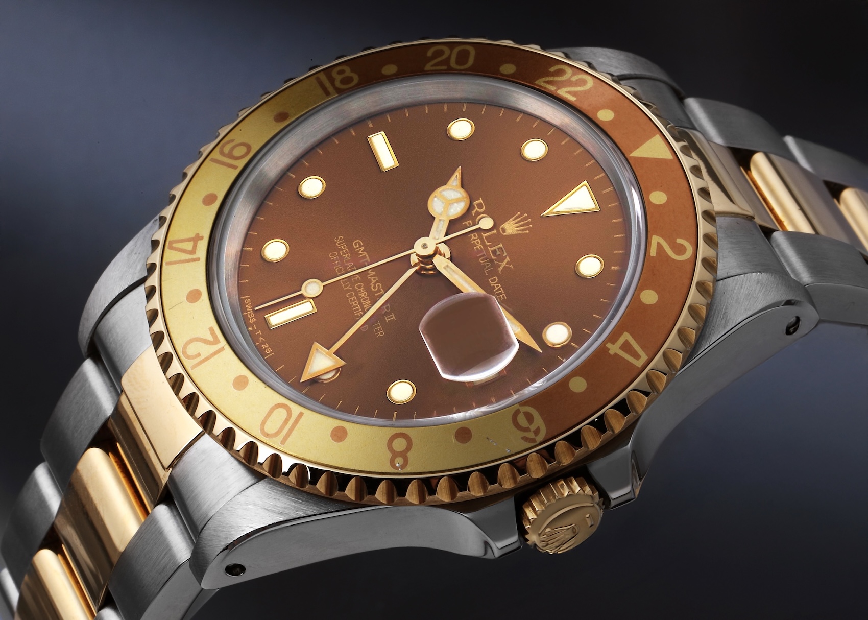 Close up of a Rolex GMT-Master II 16713 Root Beer showing the warm brown sunburst dial and slightly faded two-tone aluminum bezel.