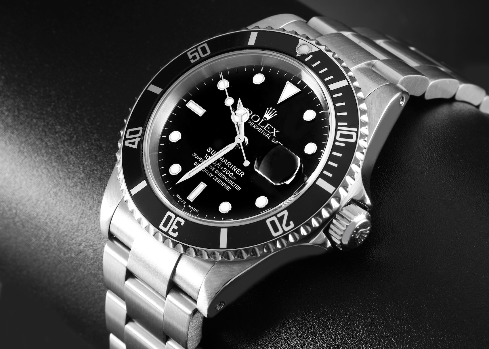 The iconic Rolex Submariner Date Reference 16610 resting on a dark surface, highlighting its black dial, aluminum bezel, and cyclops date magnifier.