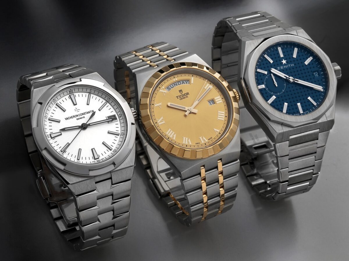 Three luxury watches with integrated bracelets (Vacheron Constantin Overseas steel, Tudor Royal two-tone, Zenith Defy Skyline steel) displayed together in a row.
