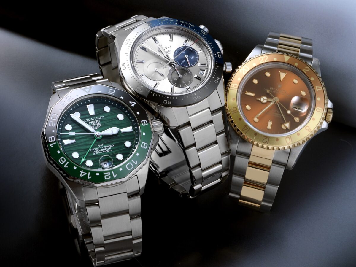 Group of three luxury men's watches featuring a green TAG Heuer Aquaracer, silver Zenith Chronomaster Sport, and two-tone Rolex GMT-Master II Root Beer.