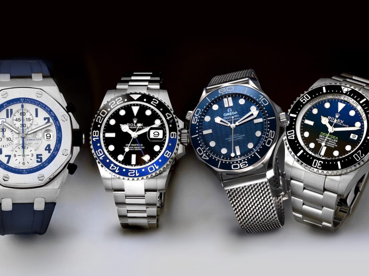 A collection of four luxury men's sports watches including an Audemars Piguet Royal Oak Offshore, Rolex GMT-Master II Batman, Omega Seamaster, and Rolex Deepsea.