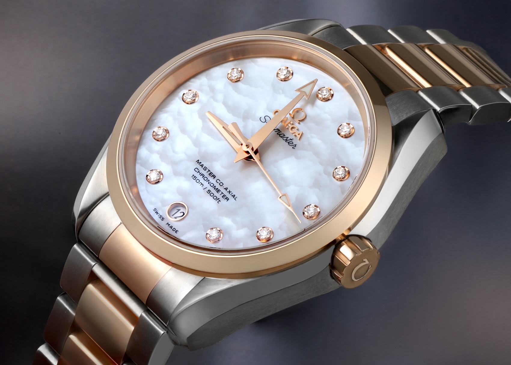 Macro shot of an Omega Aqua Terra in two-tone 18k rose gold and steel, featuring a white mother-of-pearl dial and diamond hour markers.