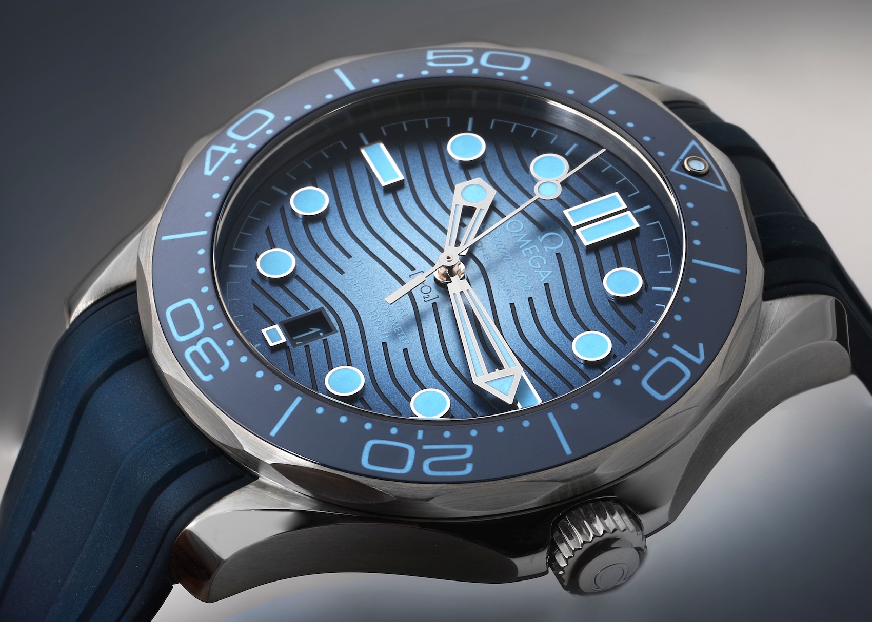Macro view of the Omega Seamaster Diver 300M Co-Axial Master Chronometer with a gradient Summer Blue wave dial on a blue rubber strap.
