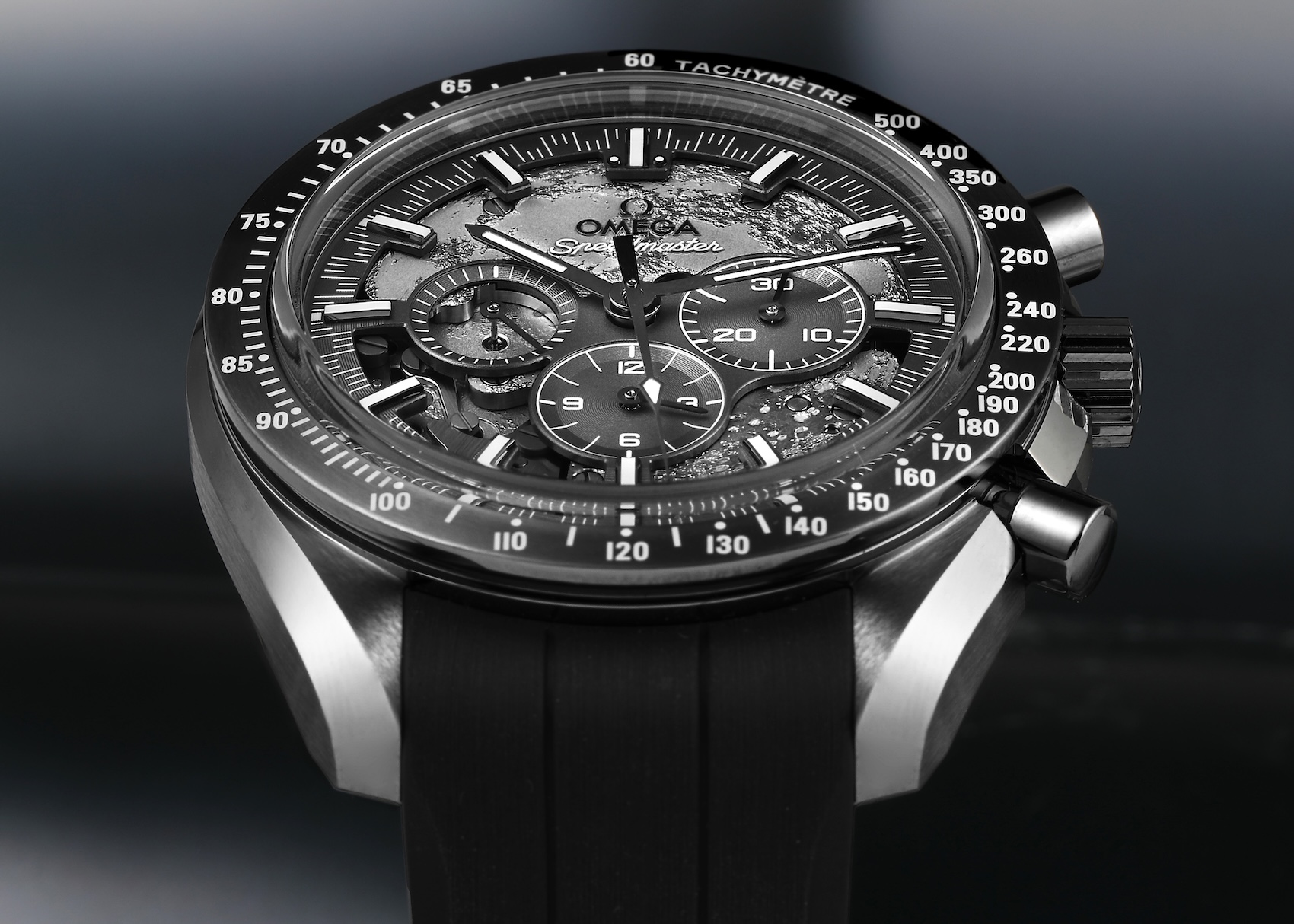 Side angled profile of the Omega Speedmaster Grey Side of the Moon showing the brushed grey ceramic case, tachymeter scale, crown, and chronograph pushers.
