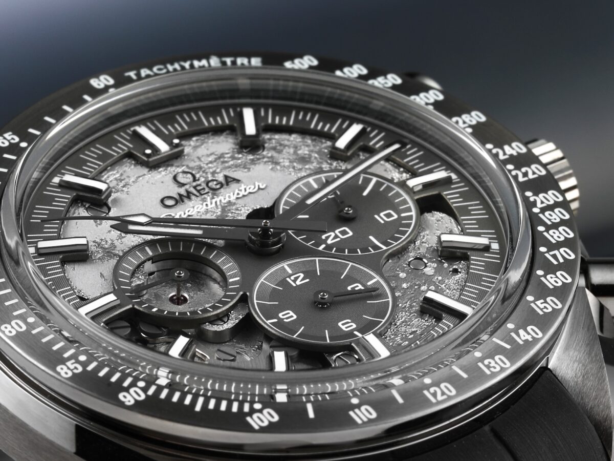 Extreme macro close-up of the skeletonized dial on the Omega Speedmaster Grey Side of the Moon, revealing the cratered texture and exposed mechanical gears.