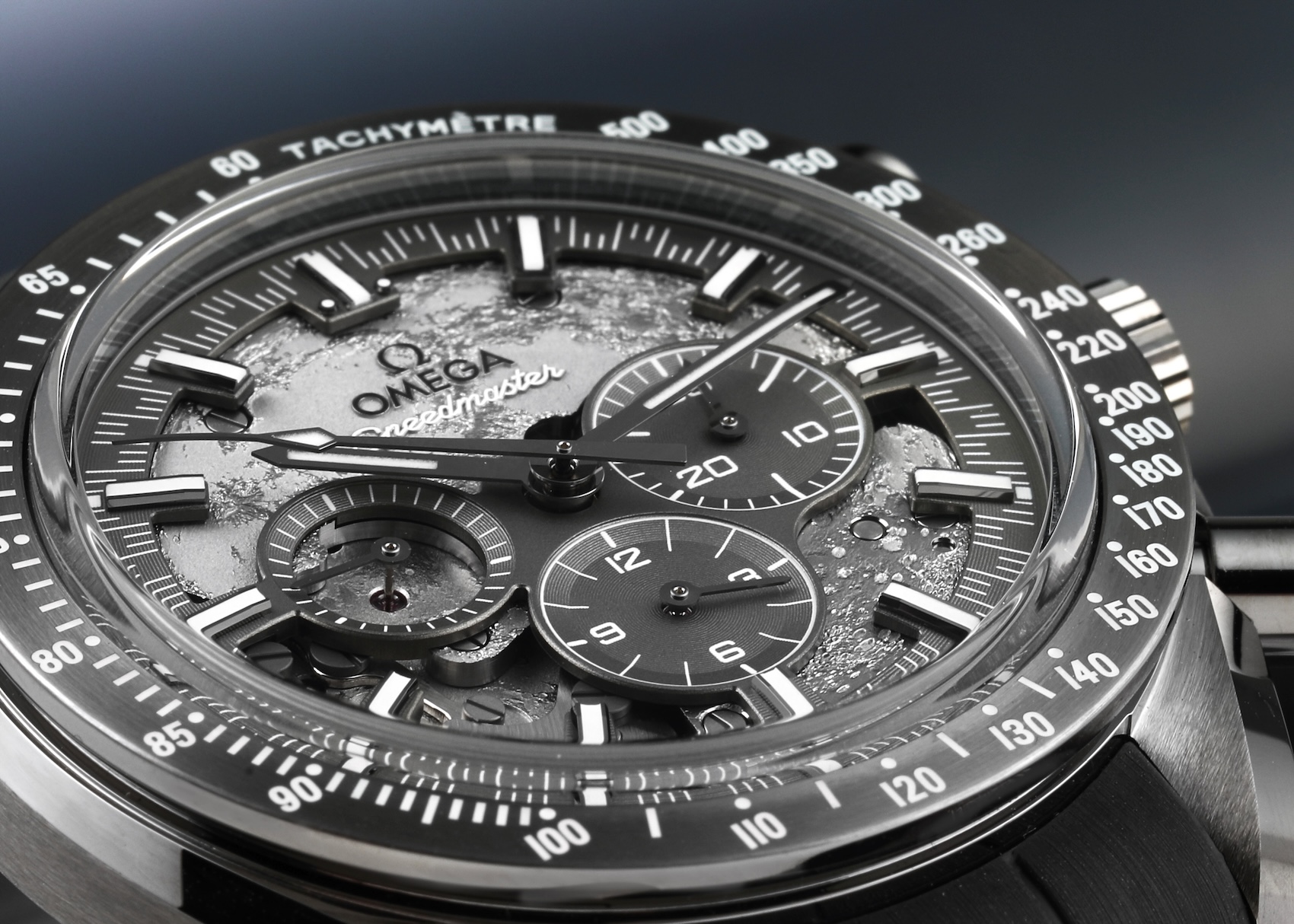 Extreme macro close-up of the skeletonized dial on the Omega Speedmaster Grey Side of the Moon, revealing the cratered texture and exposed mechanical gears.