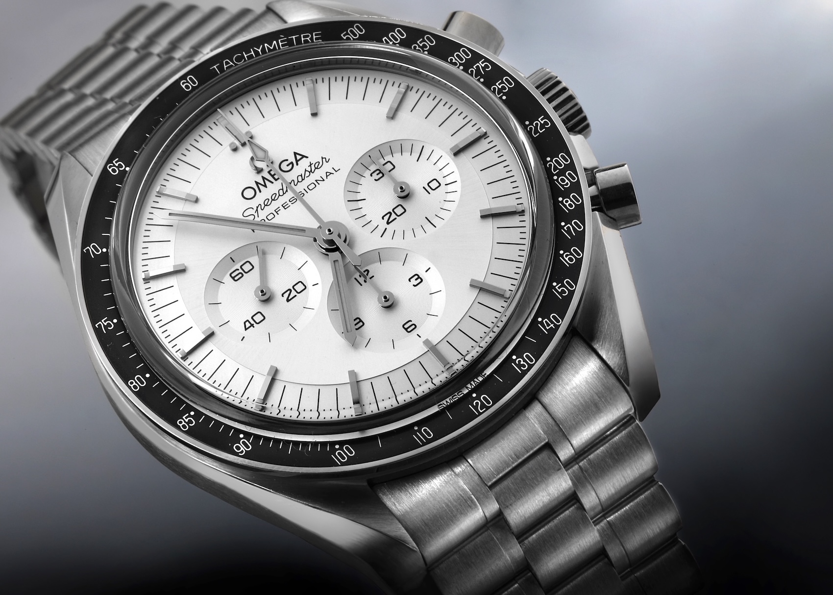 Close-up of the solid 18k white gold Omega Speedmaster Moonwatch Professional Chronograph with a sunray silver dial and black bezel.